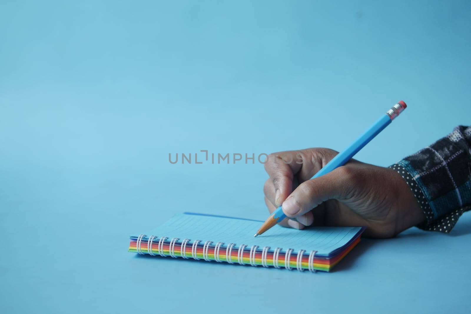 man hand writing on notepad while sited ,