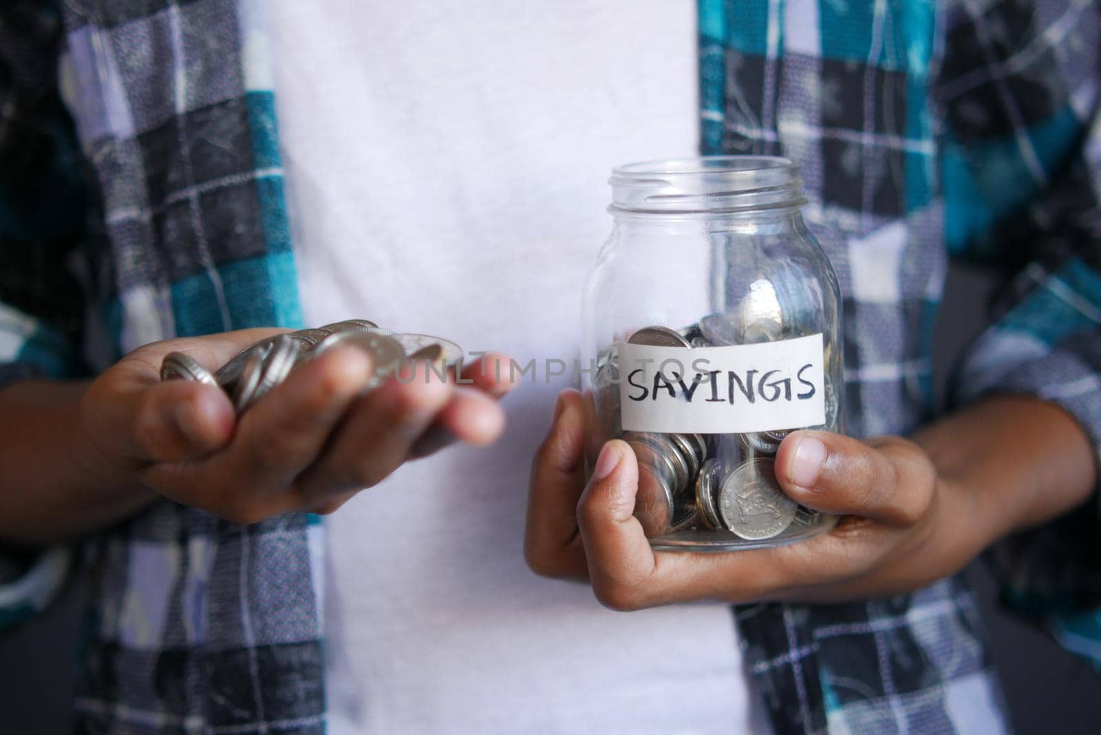 young man saving coins in a jar white sited .
