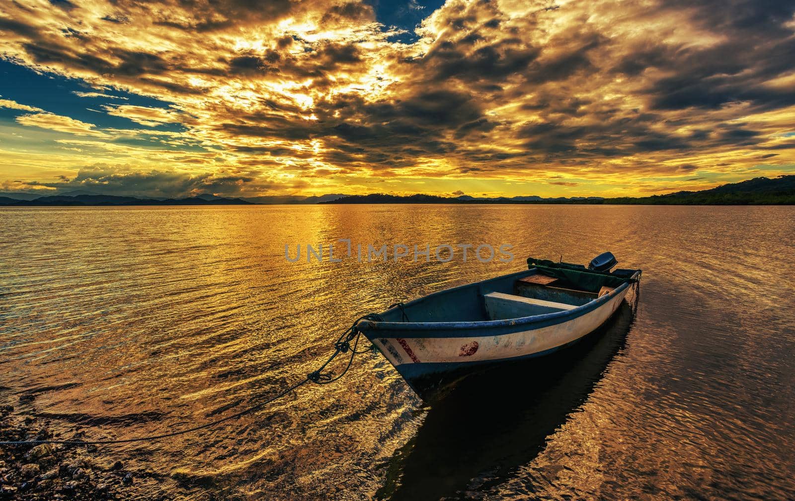 Idyllic evening view of the Pacific Coast in Muelle Conchal with boat in front against dramatic clouds. Idyllic sunset landscape. Colorado, Costa Rica. Pura Vida concept, travel to exotic tropical country.