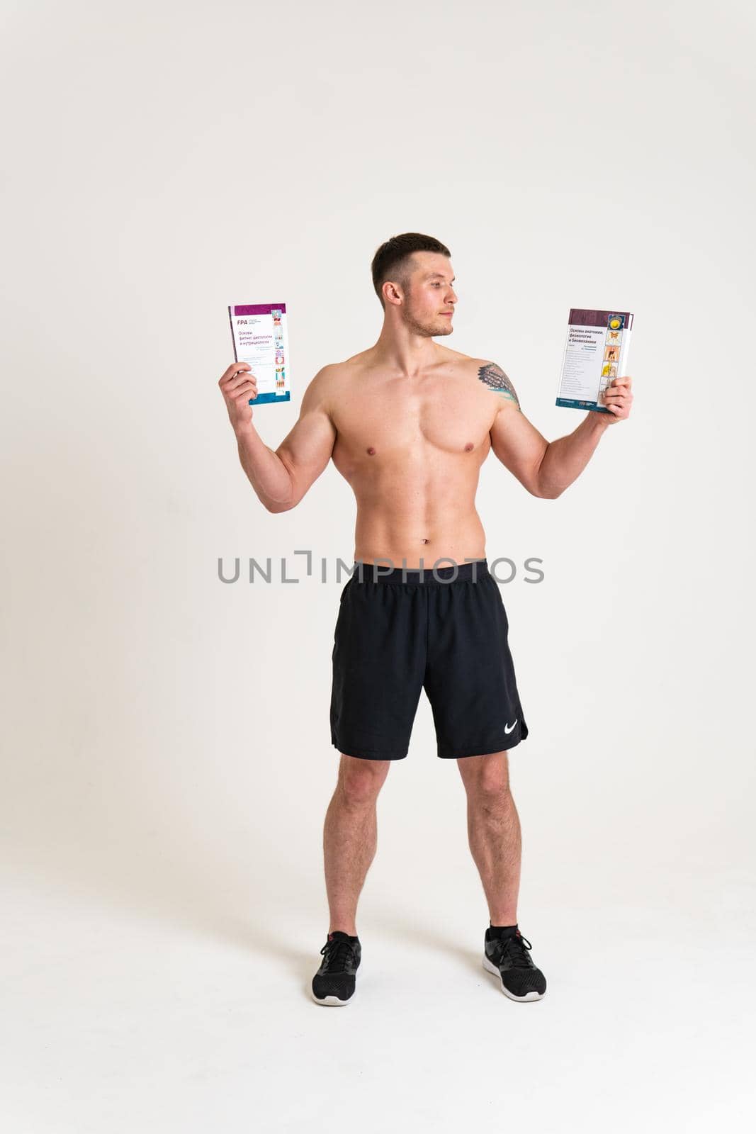 Bodybuilder reads the book on a white background isolated at the bottom of his head on his hands macho, muscle fitness chest european sport. Smile biceps, beach tan