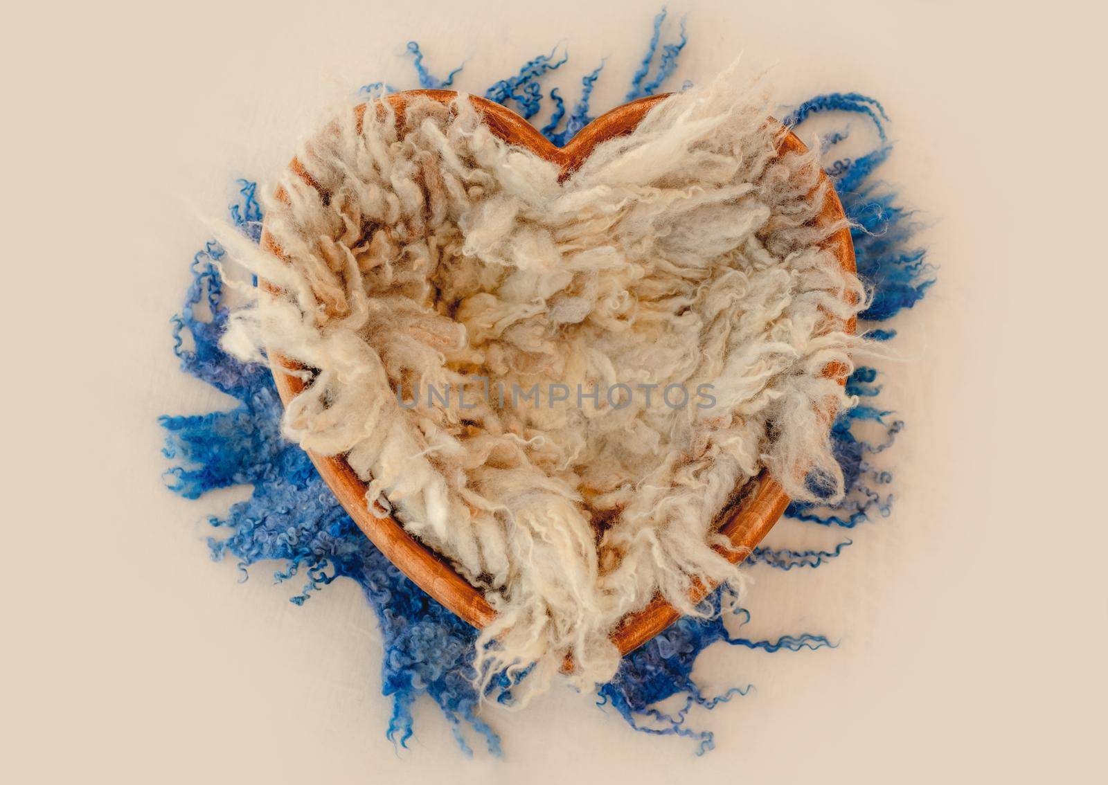 Newborn baby studio furniture in heart shape filled with fur for infant kid photoshoot. Tiny wooden bed with faux