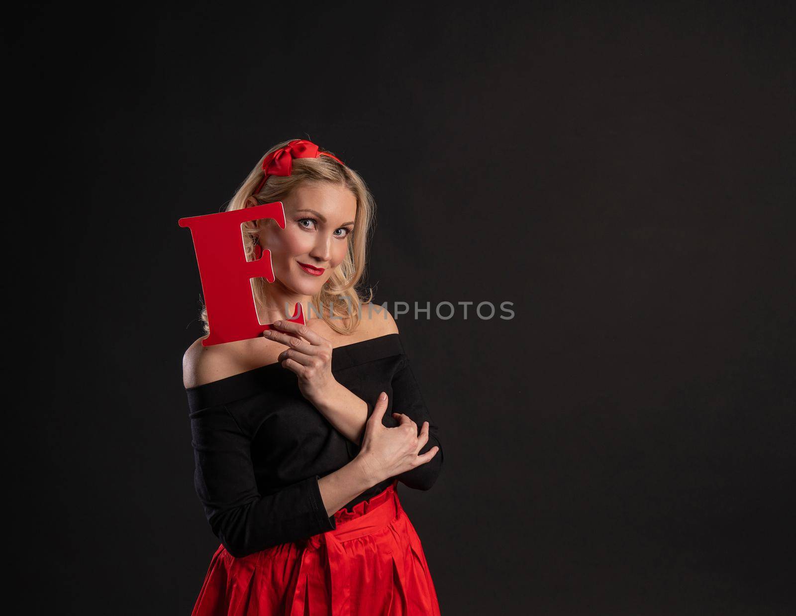 A girl holds the letters of the word LOVE valentine symbol, heart Valentine's day, on the floor hearts romance wedding. shape. formula of love, gift in red dress girl, barefoot
