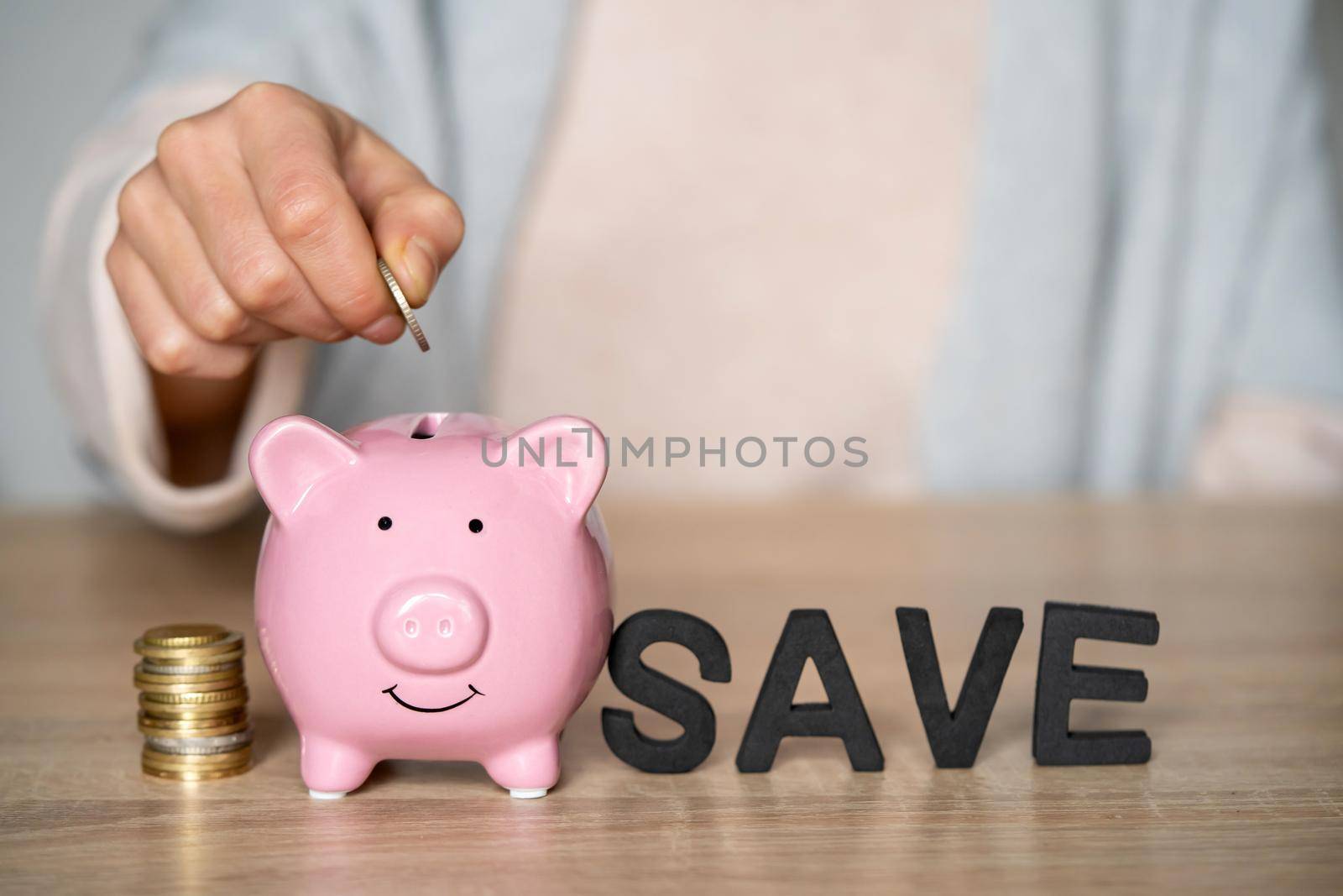 Girl with a piggy bank with coins and the inscription save, folder from letters on the table, woman's hands with savings close-up.