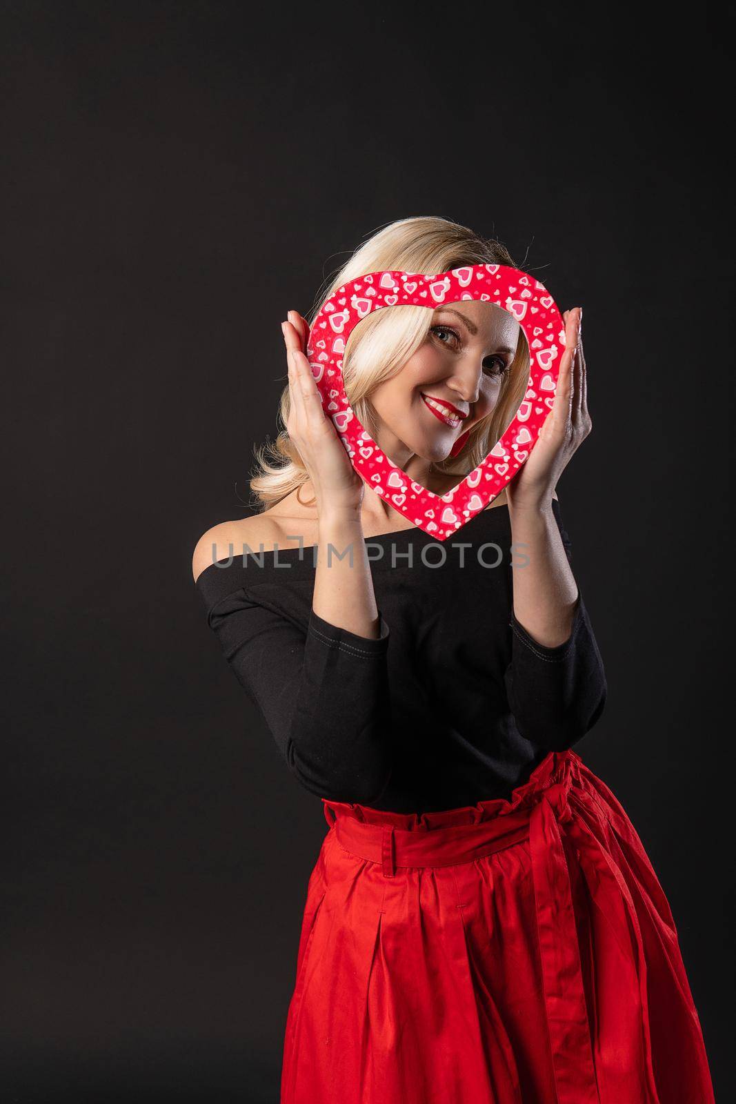 Girl holding a heart at eye level red, flirting, on the floor hearts wedding. inspiration banner. love formula of love, black in red dress girl, barefoot by 89167702191