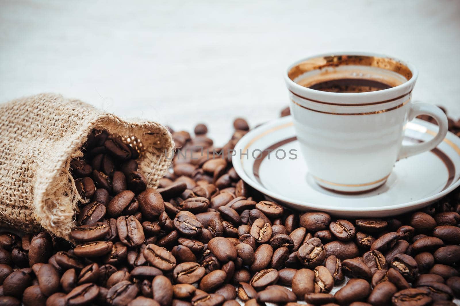 Coffee cup and beans on a biege burlap background. roasted coffee beans