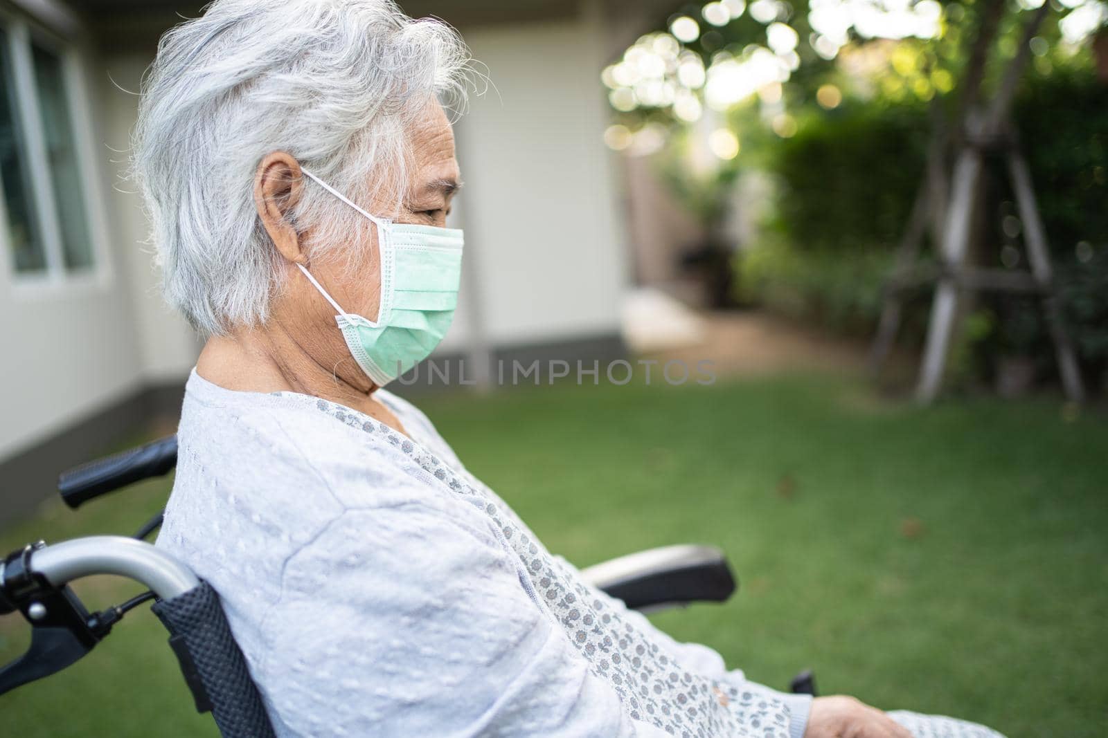 Asian senior or elderly old lady woman on wheelchair and wearing a face mask for protect safety infection Covid-19 Coronavirus in park. by pamai