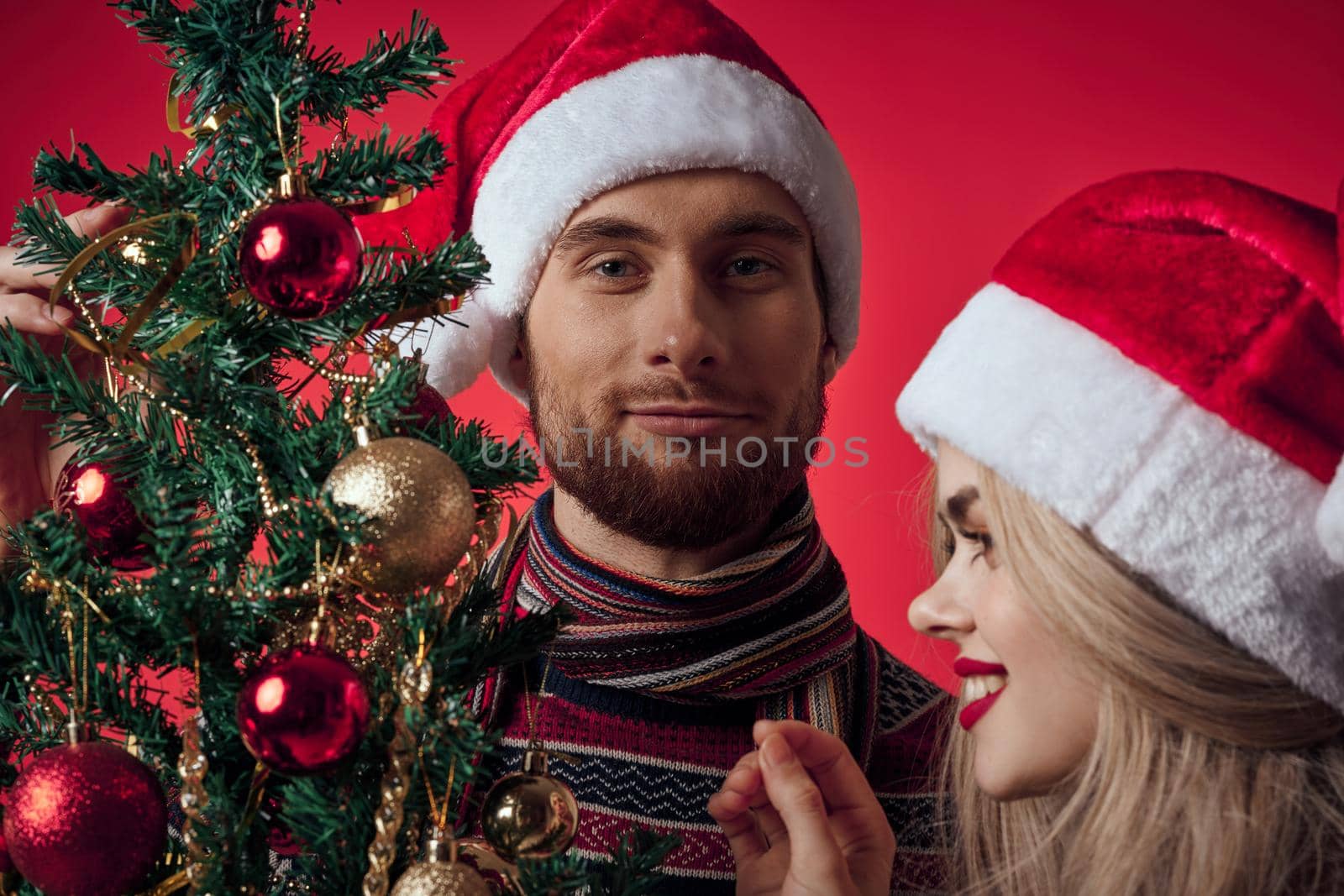 cute man and woman new year tree decoration holiday red background. High quality photo
