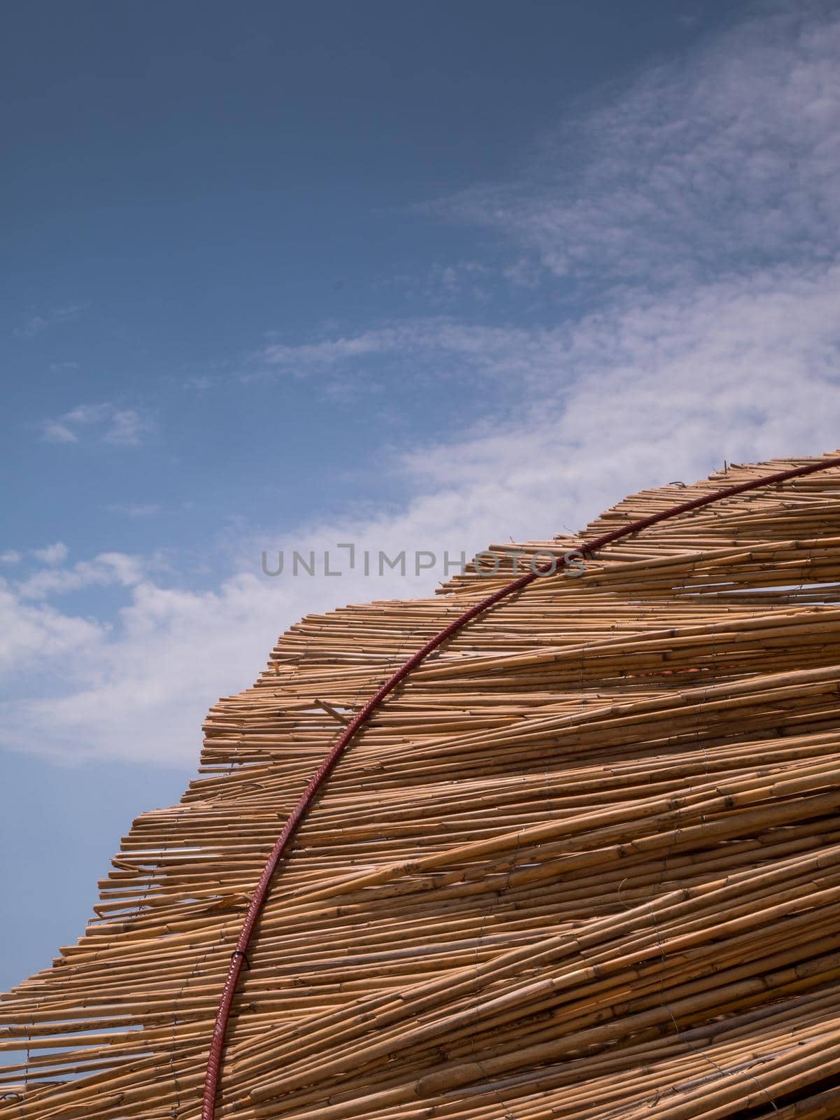 Part of the straw beach umbrellas and View of the beautiful blue sky with little clouds