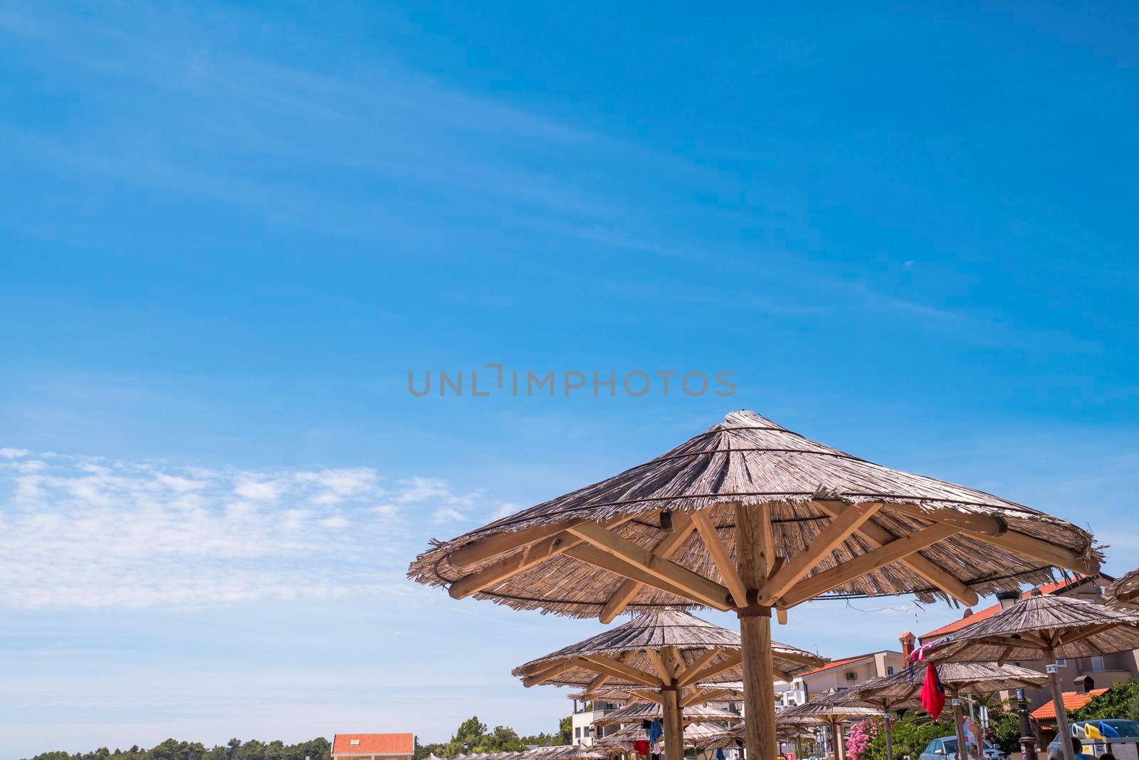 View of the beautiful blue sky and straw beach umbrellas by zebra