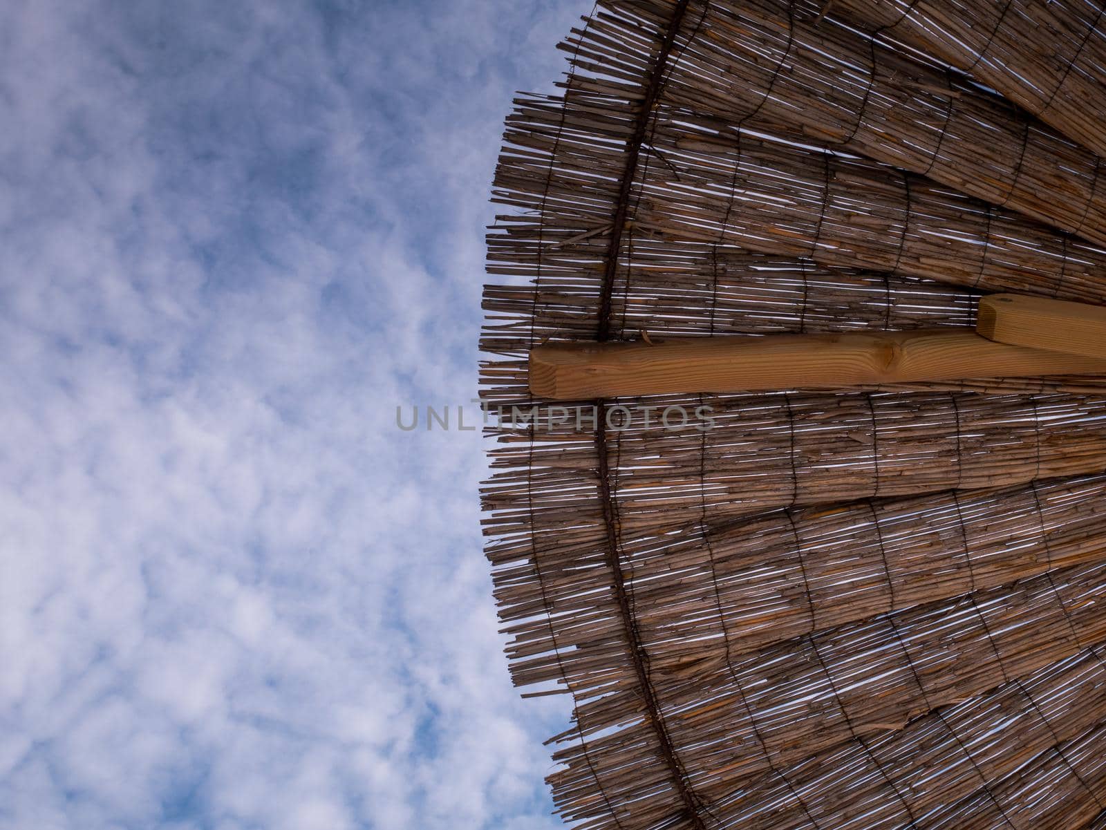 Part of the straw beach umbrellas and View of the beautiful blue sky with little clouds