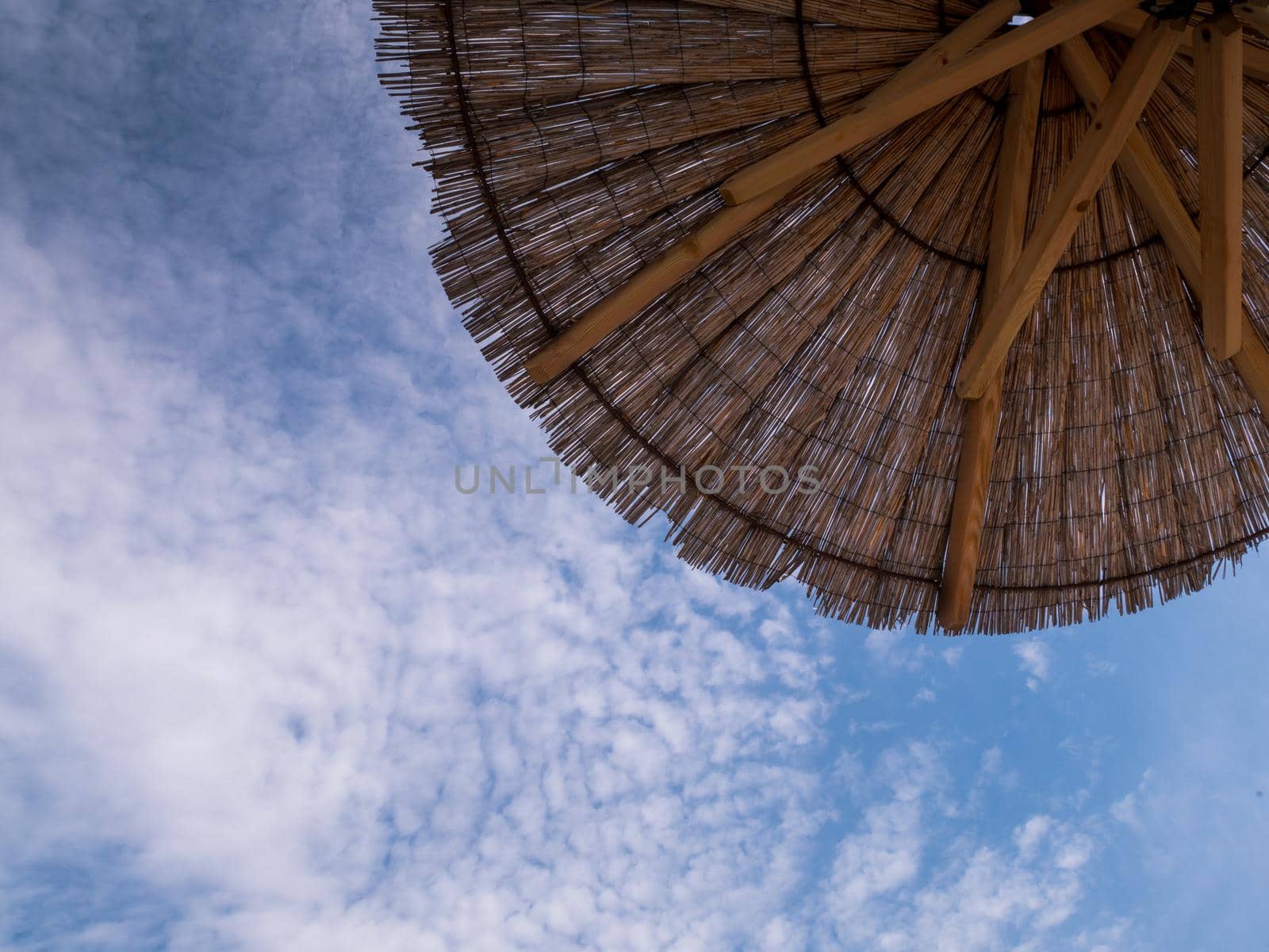 Part of the straw beach umbrellas and View of the beautiful blue sky with little clouds