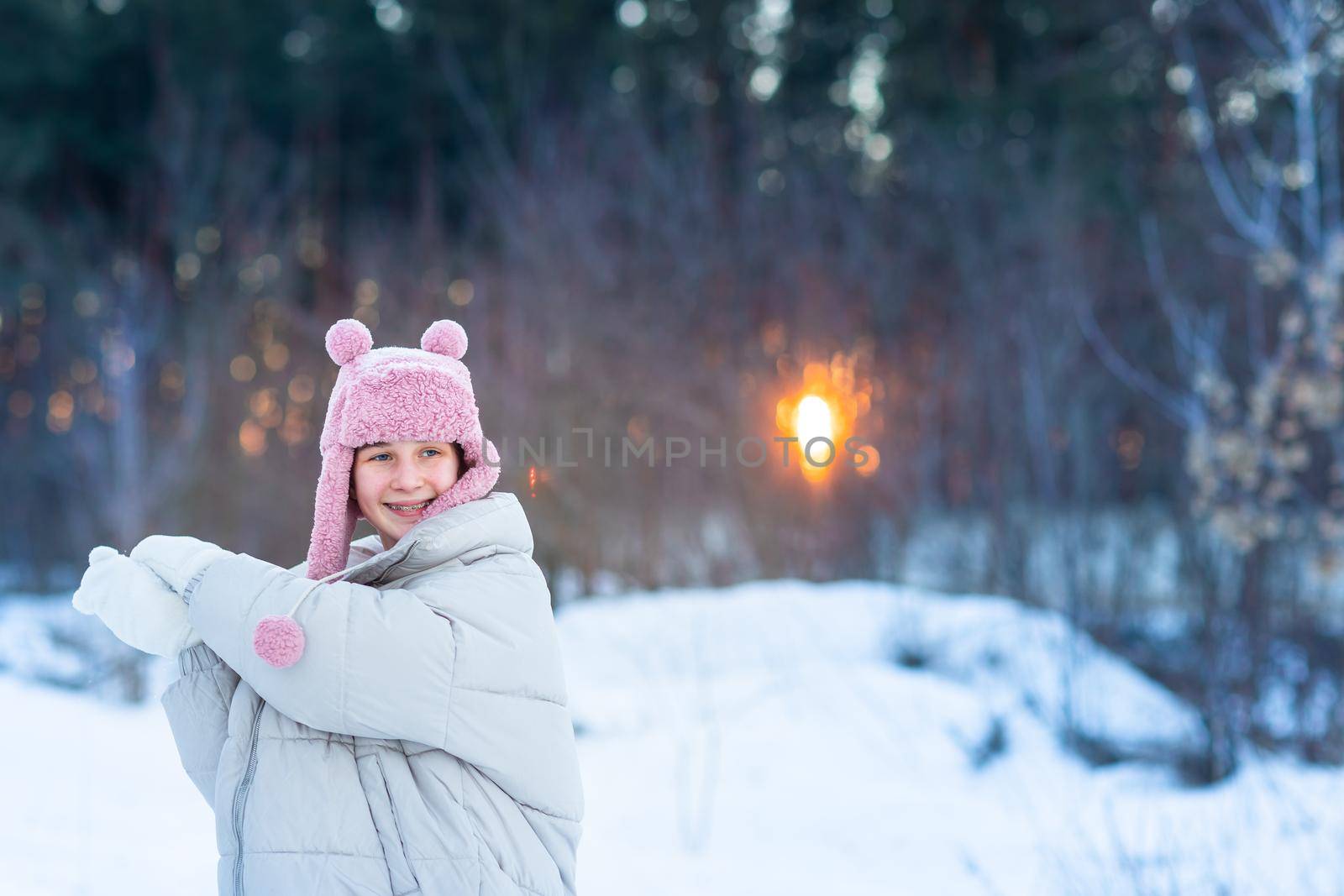 Cute little teenage girl having fun playing with snowballs, ready to throw the snowball. Snow games. Winter vacation.