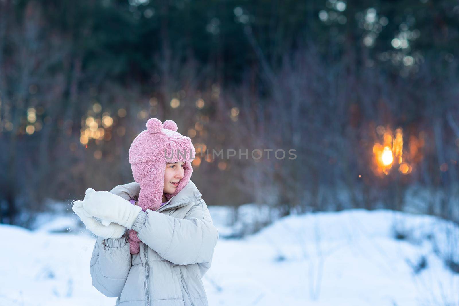 Cute little teenage girl having fun playing with snowballs, ready to throw the snowball. Snow games. Winter vacation.