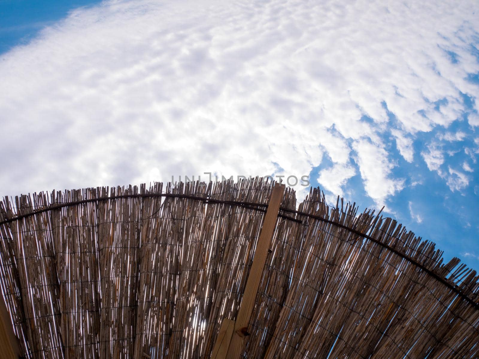 Part of the straw beach umbrellas and View of the beautiful blue sky with little clouds