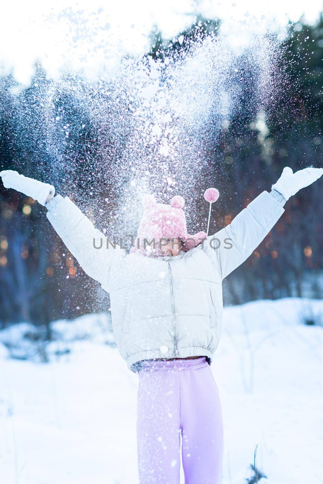 Cute little teenage girl having fun playing with snowballs, ready to throw the snowball. Snow games. Winter vacation.
