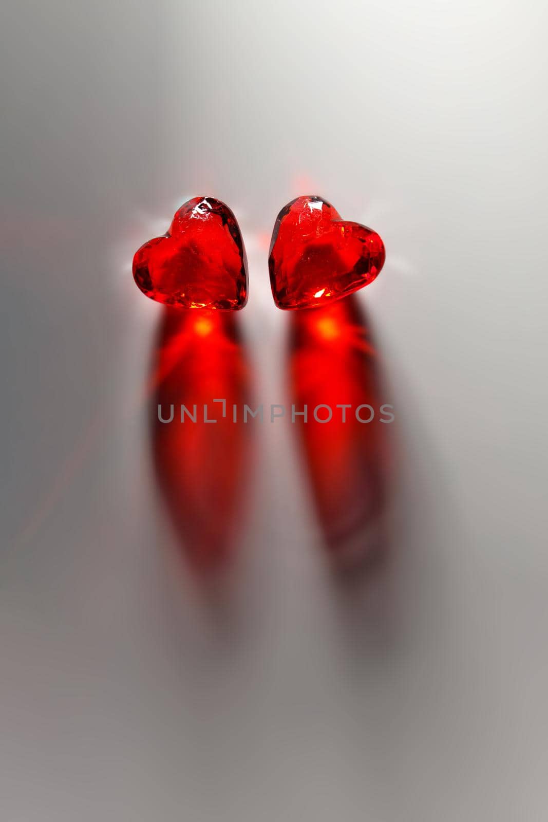 Directly Above Studio mage of Two Sparkling Red Gemstone Hearts, side-by-side, on a Grey Studio Background. This image is dramatically lit and has plenty of Copy Space.