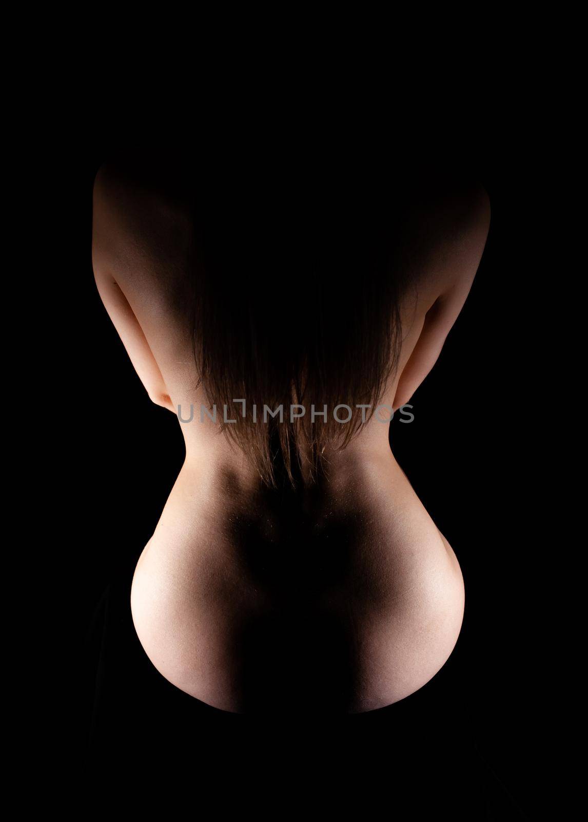 silhouette of a slender woman from the back on a black background. Soft focus. Non-Explicit Nudity