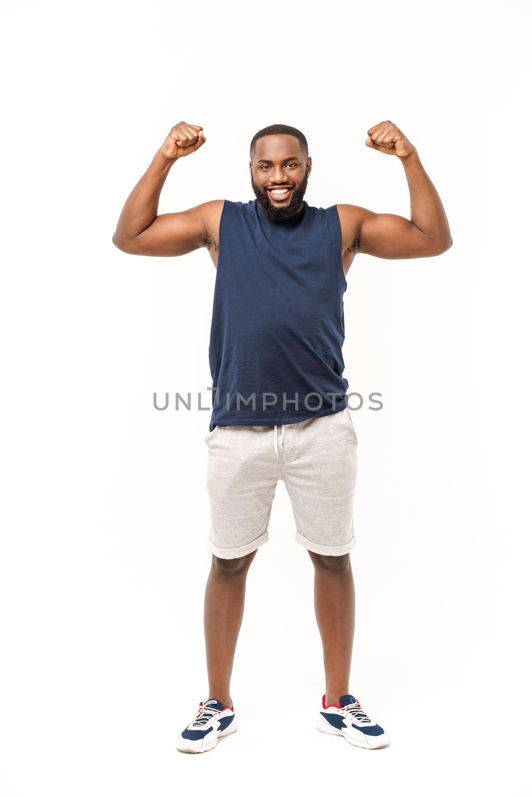African American teenager shows muscles on arm. Isolated on white background. Studio portrait. Transitional age concept by Benzoix