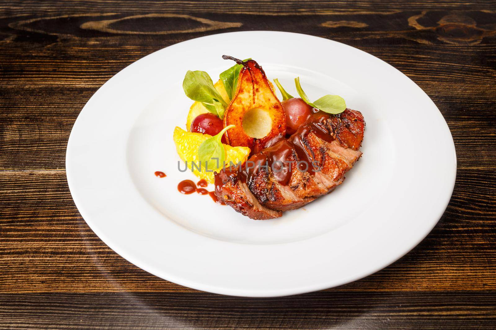 Grilled pork steak with caramel pear, orange and grape served on white pate