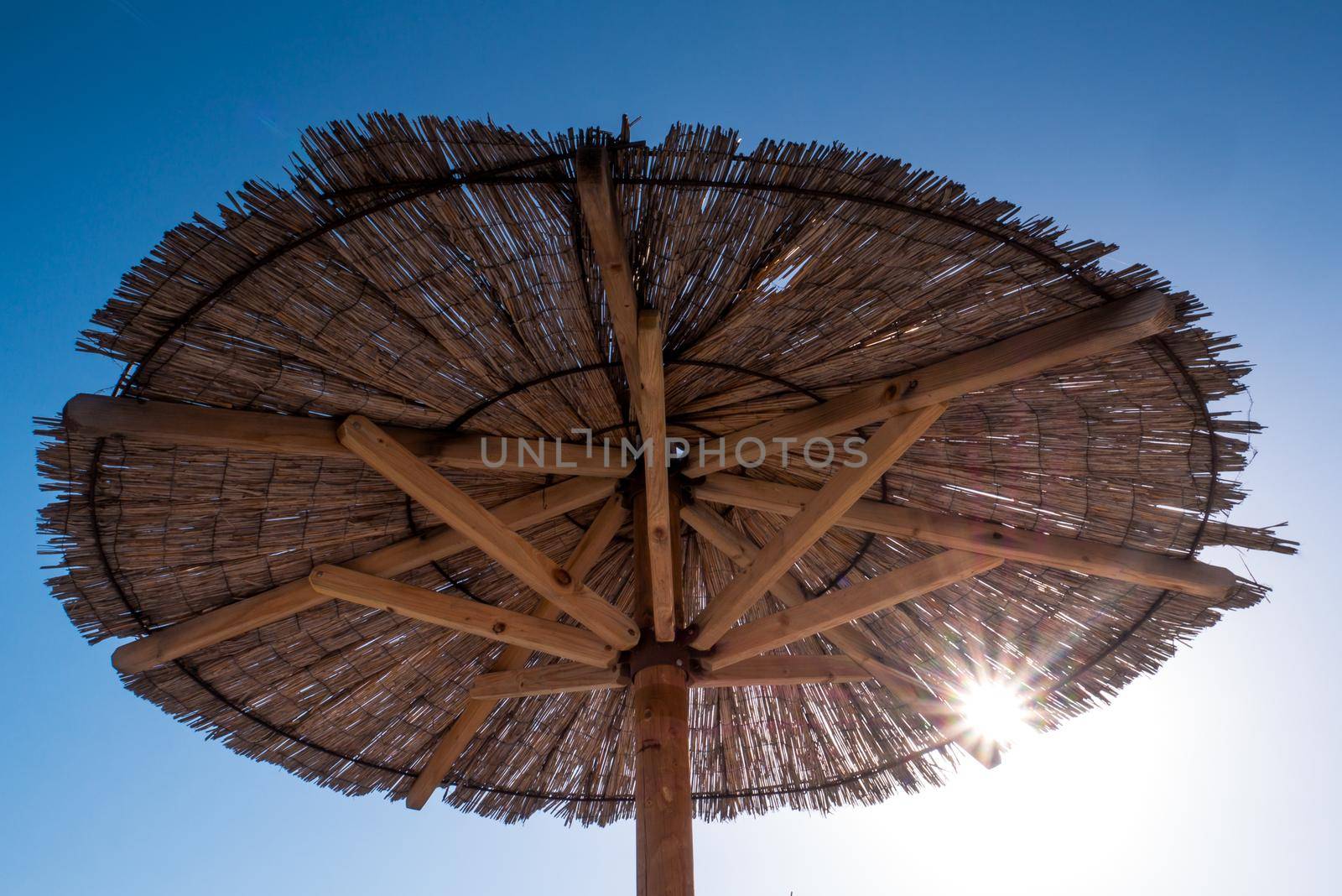 Beach umbrella, view of the beautiful blue sky and straw beach umbrella. Perfect holiday concept. Travel and vacation. Beach on Vir Island, Croatia, Europa. Copy space.