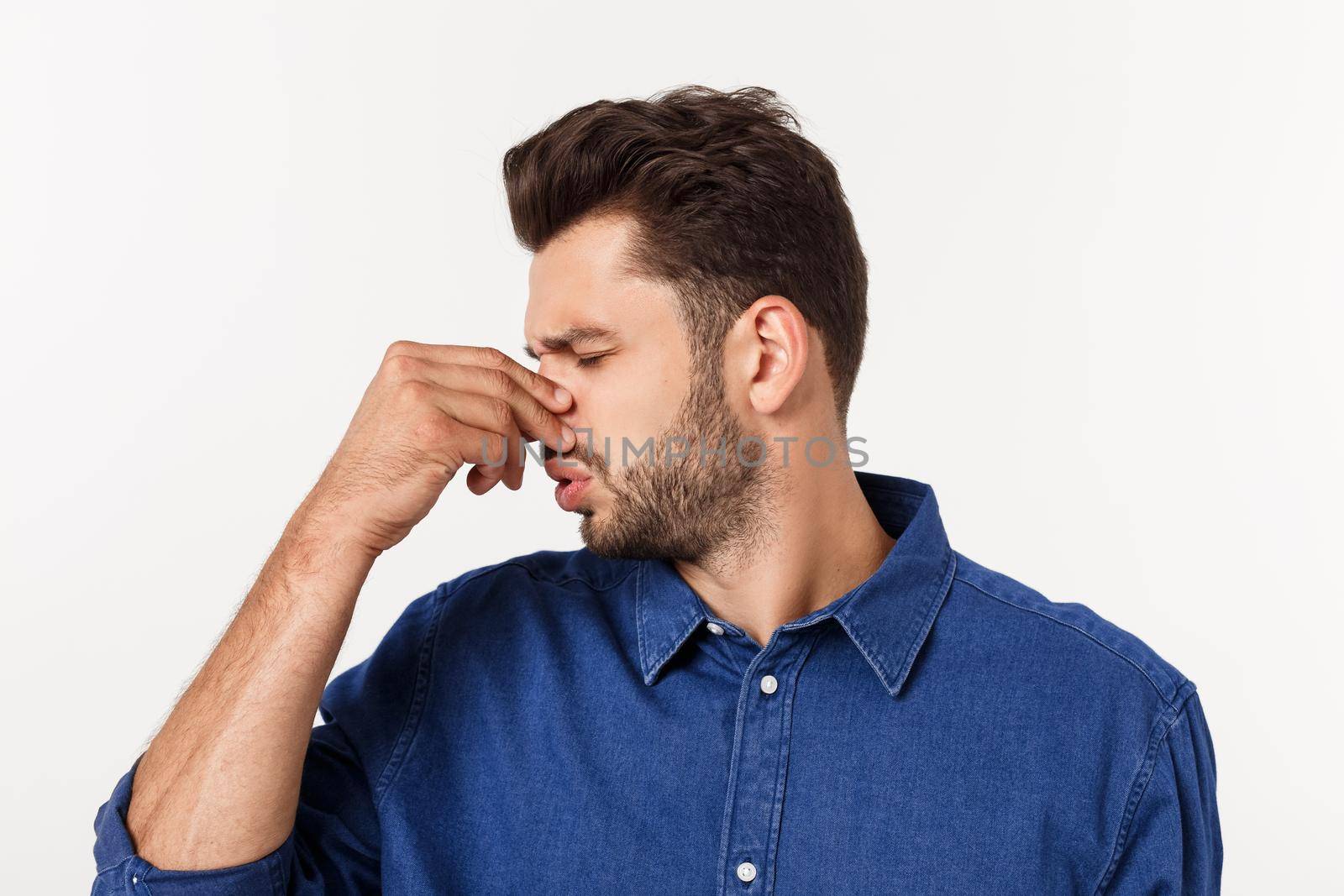Man holding his nose against a bad smell isolated over grey background. by Benzoix