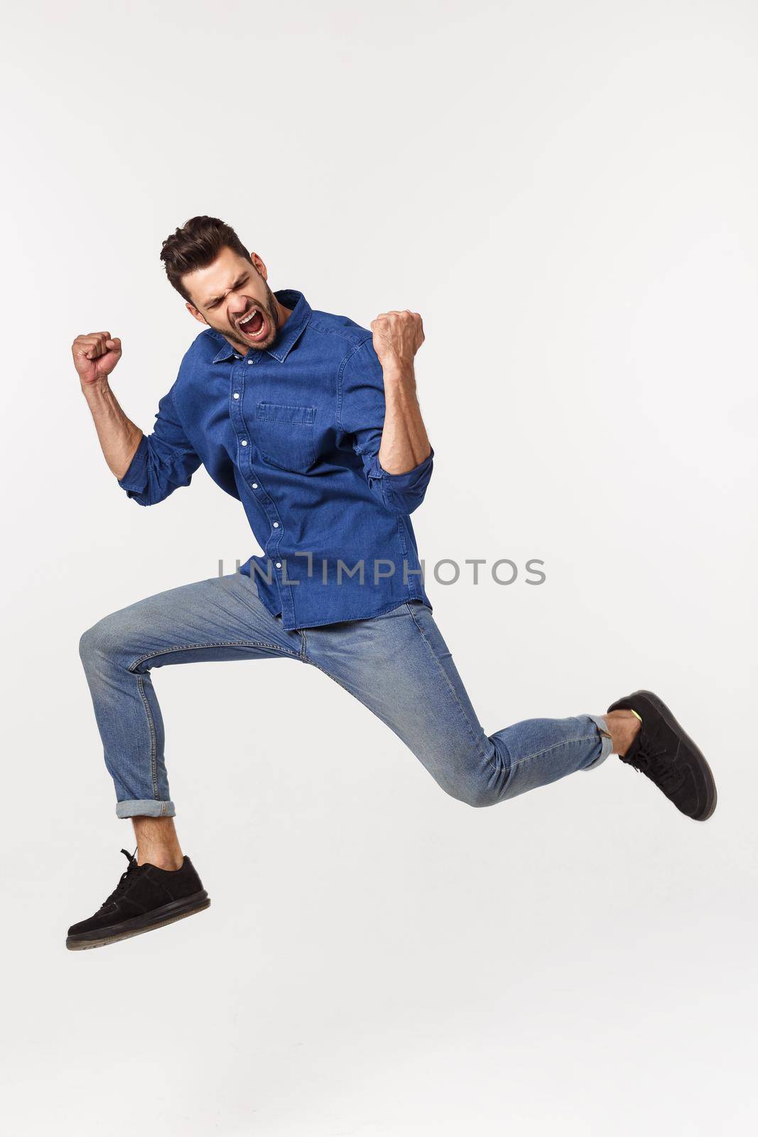 An attractive athletic businessman jumping up against white background.