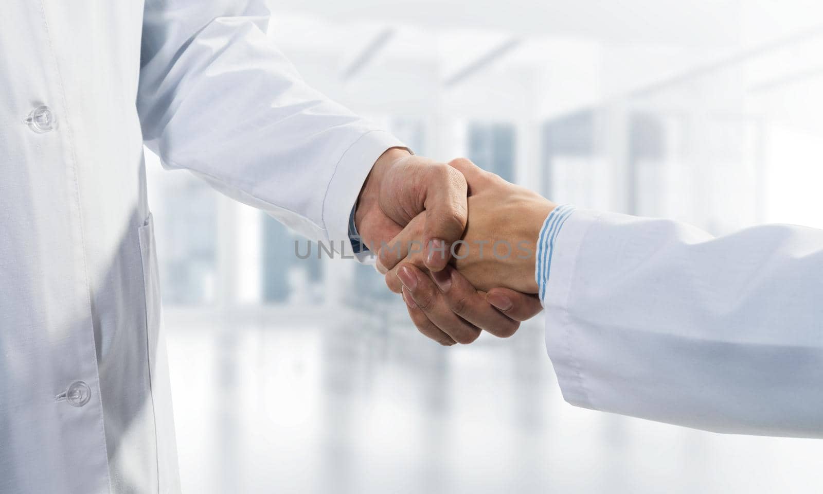 Close-up of the handshake between the two medics. Against the backdrop of the office