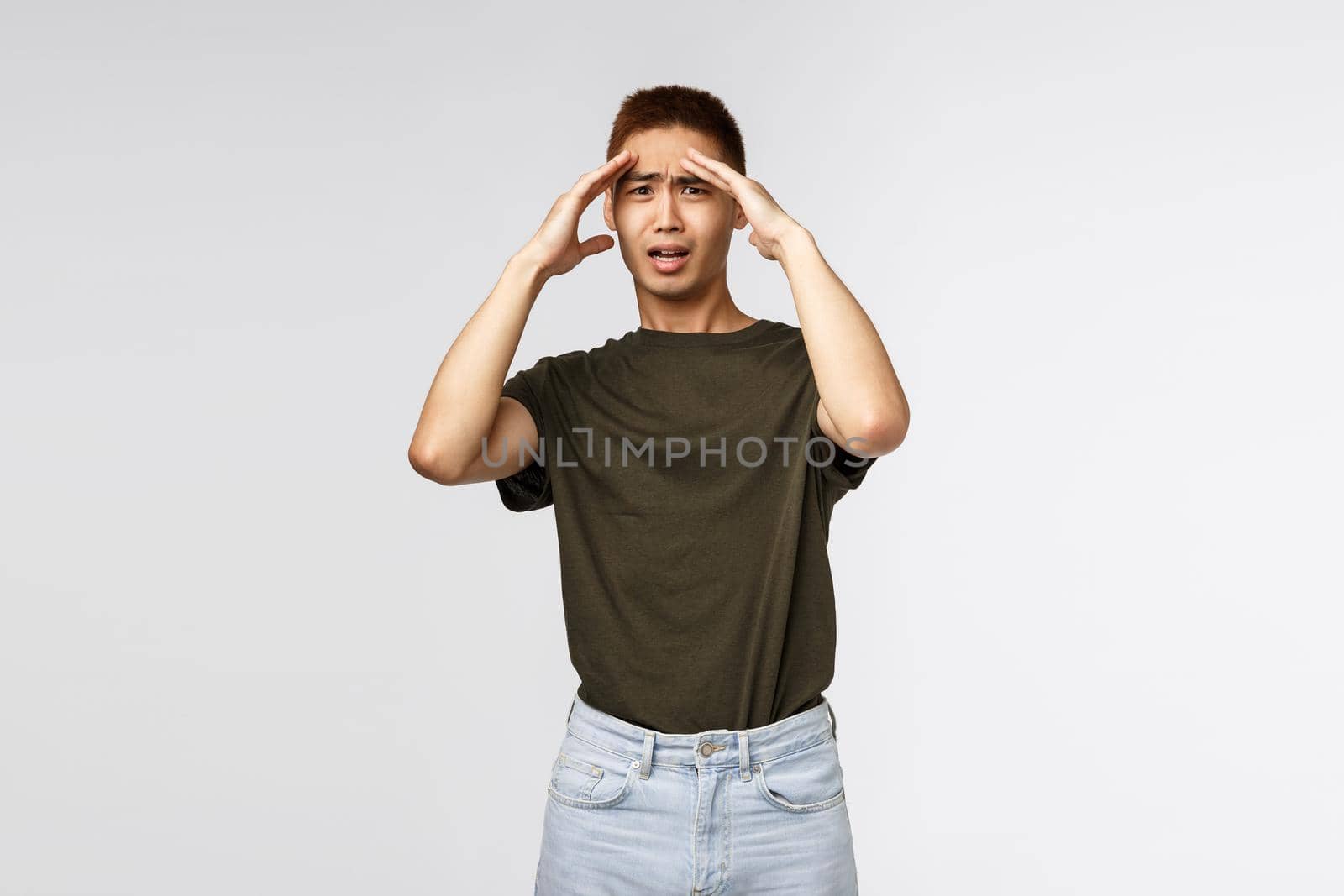 Gosh its insane. Portrait of shocked and concerned young asian man got in trouble, touch forehead grimacing and cringing, hear bad news, shook truth, processing information, panicking by Benzoix