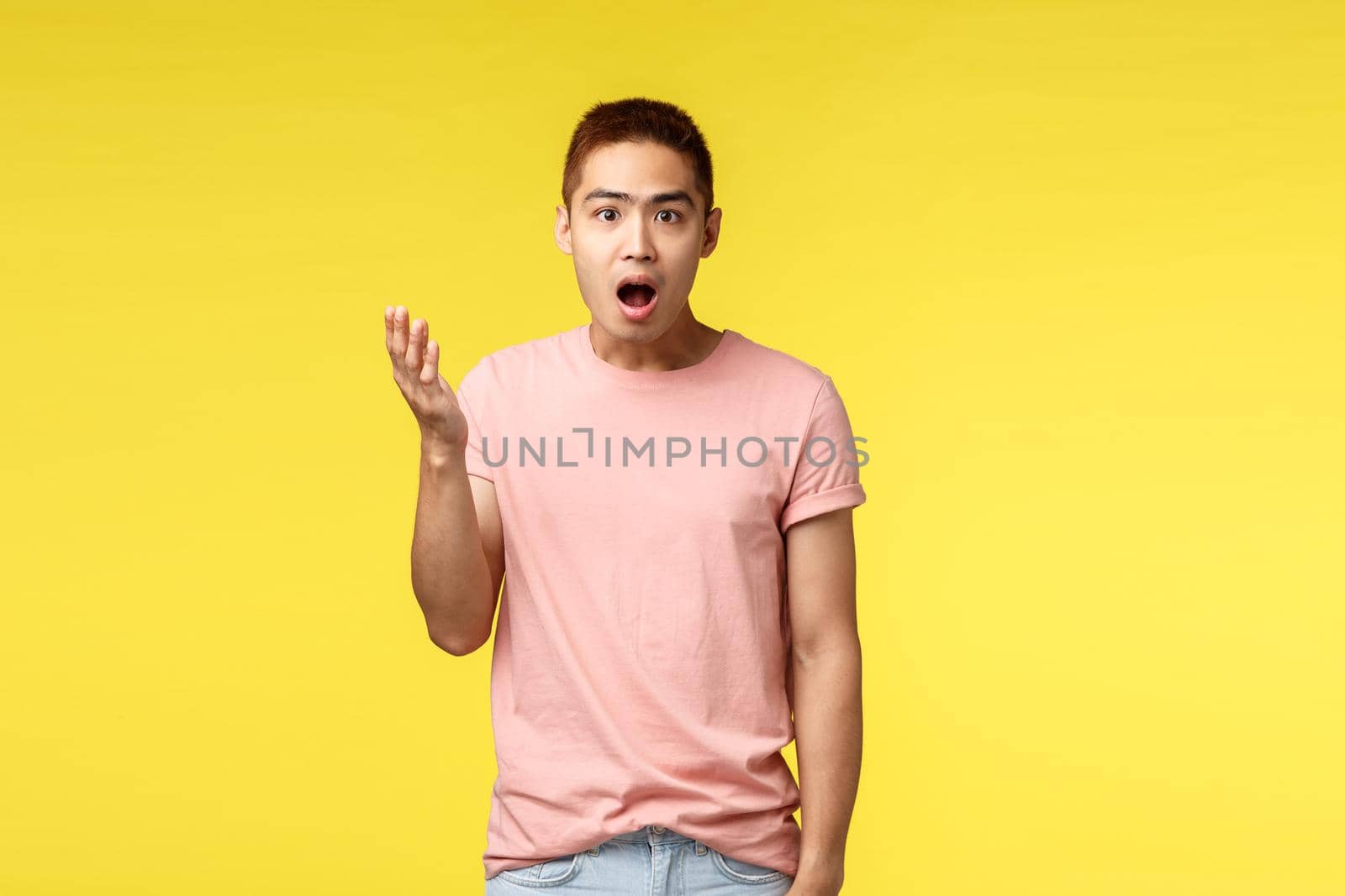 People, different emotions and lifestyle concept. Shocked, surprised and impressed asian male in pink t-shirt, stylish haircut, raise hand up and look astounded at camera, open mouth fascinated by Benzoix