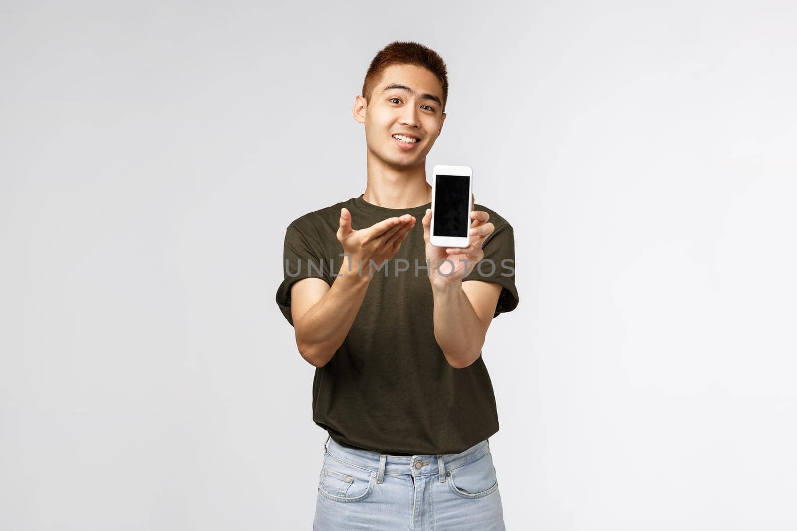 Technology, online lifestyle and communication concept. Portrait of pleased cheerful asian man introduce mobile phone application, brag with his game score, show smartphone display.