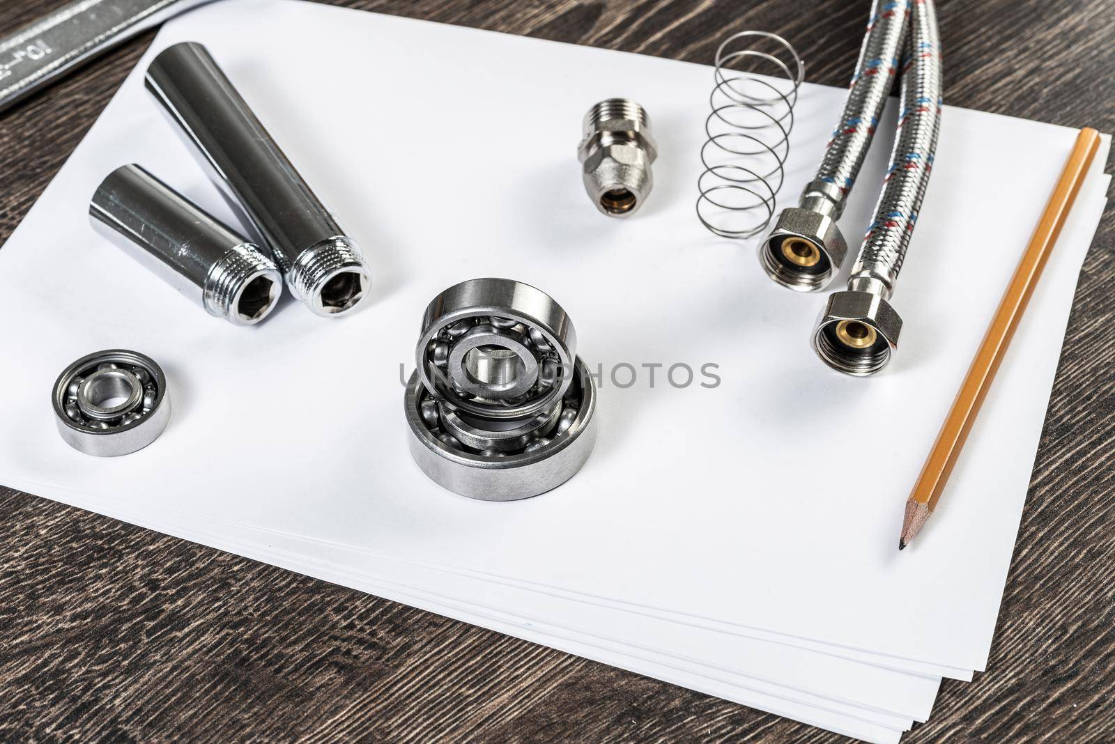 Plumbing pipeline and ball bearings laying on table. Water fittings and connections with segments of braided hose. Steel details for engine mechanisms. House infrastructure designing and installation