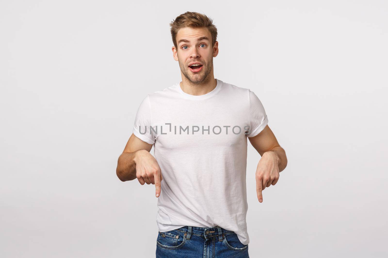 Excited, charistmastic surprised happy blond male model with bristle, pointing down joyful, sharing good news, introduce product, recommend download app, click link or banner, white background by Benzoix