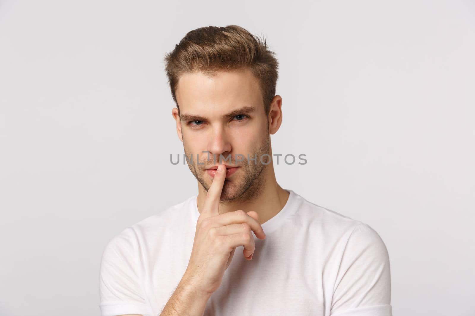 Close-up pensive and smart good-looking focused young man, touching lip and squinting pondering, hear interesting concert or suggestion, standing thoughtful, standing white background.