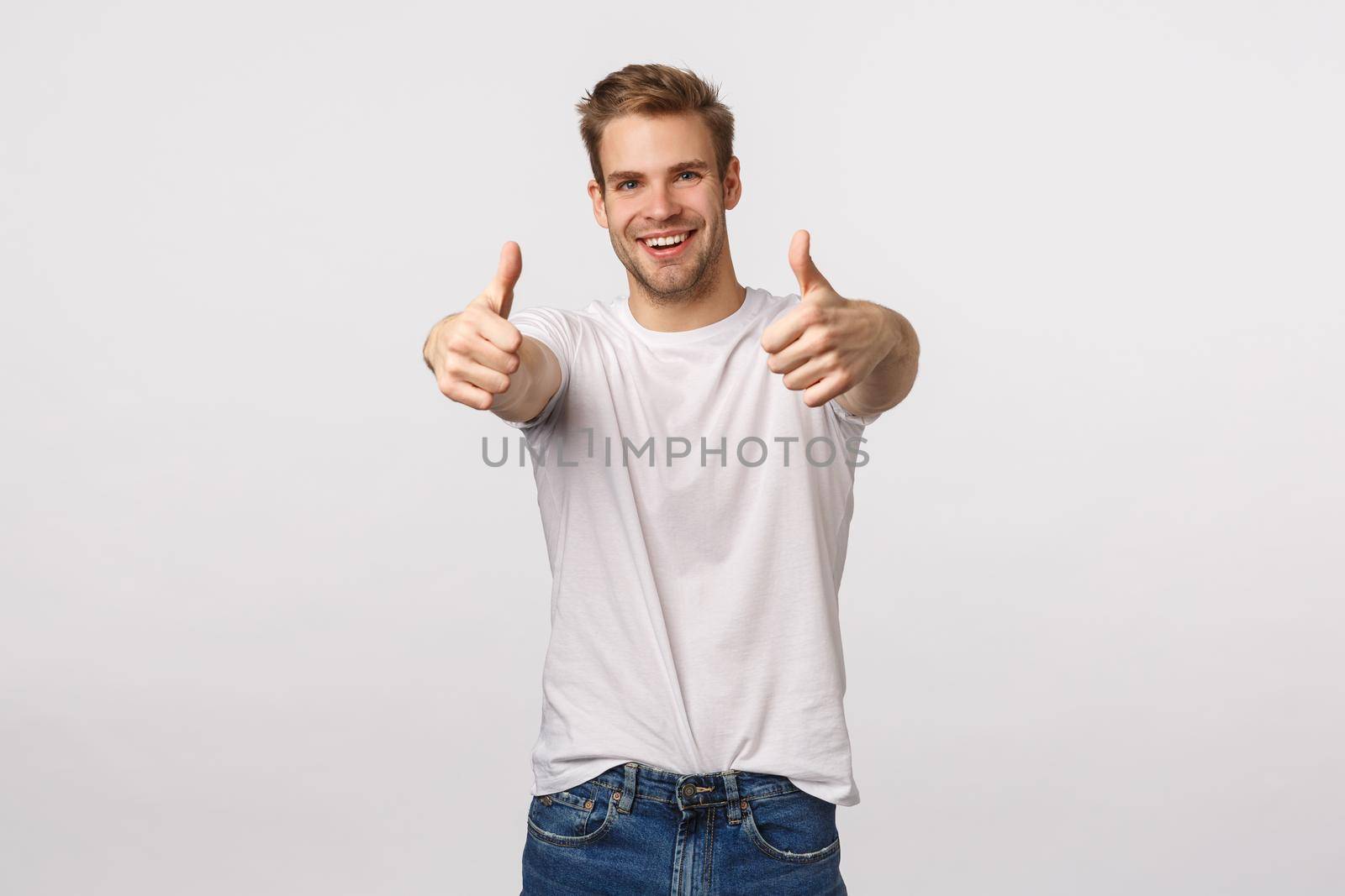Optimistic and upbeat good-looking blond caucasian guy with bristle, extend hands with thumbs-up to praise friend, congratulate with win, good effort, think product excellent, give approval.