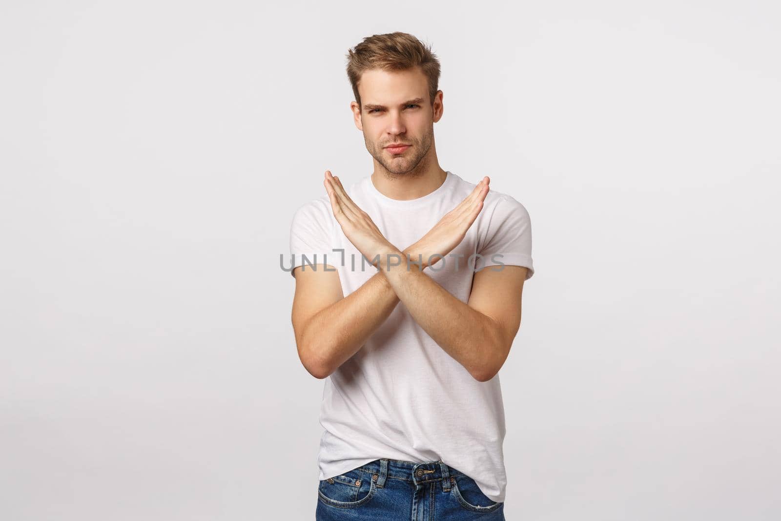 I disagree. Serious-looking blond guy with bristle making cross, stop gesture over chest and looking assertive camera, protest, give negative feedback, prohibit action, dont agree, white background.