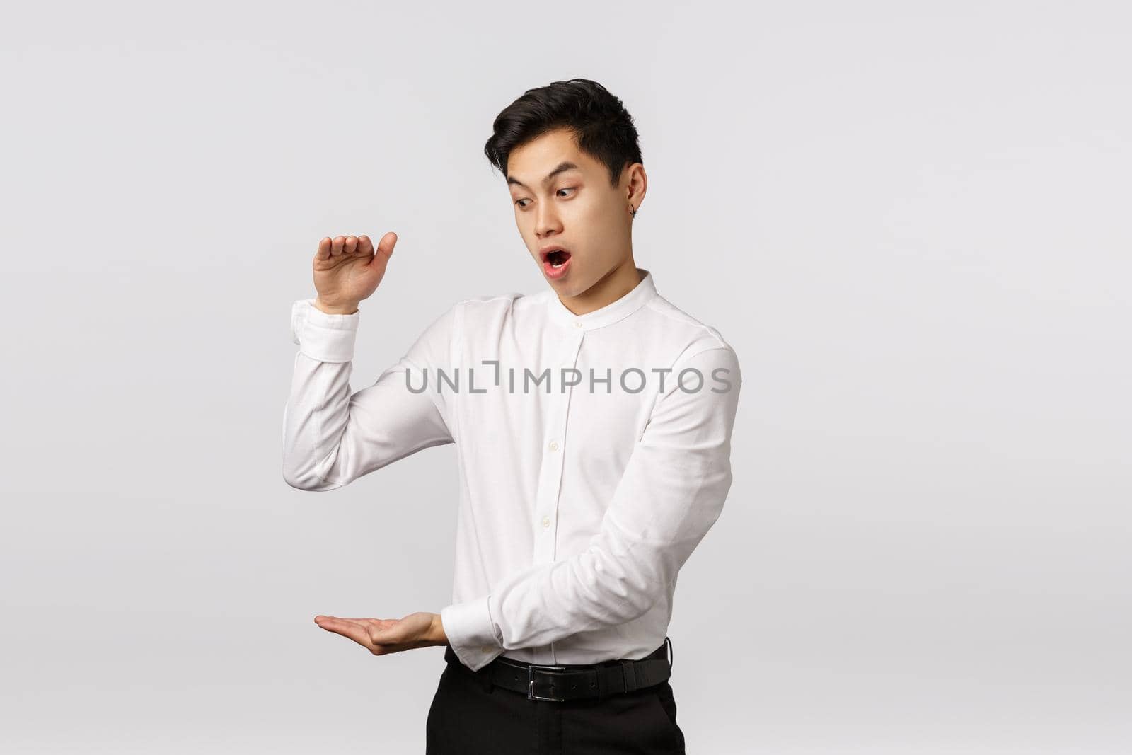 Omg businessman shocked how fast finances increase. Astonished and impressed, excited asian male employee getting rich fast, showing something big, shaping large box, white background.