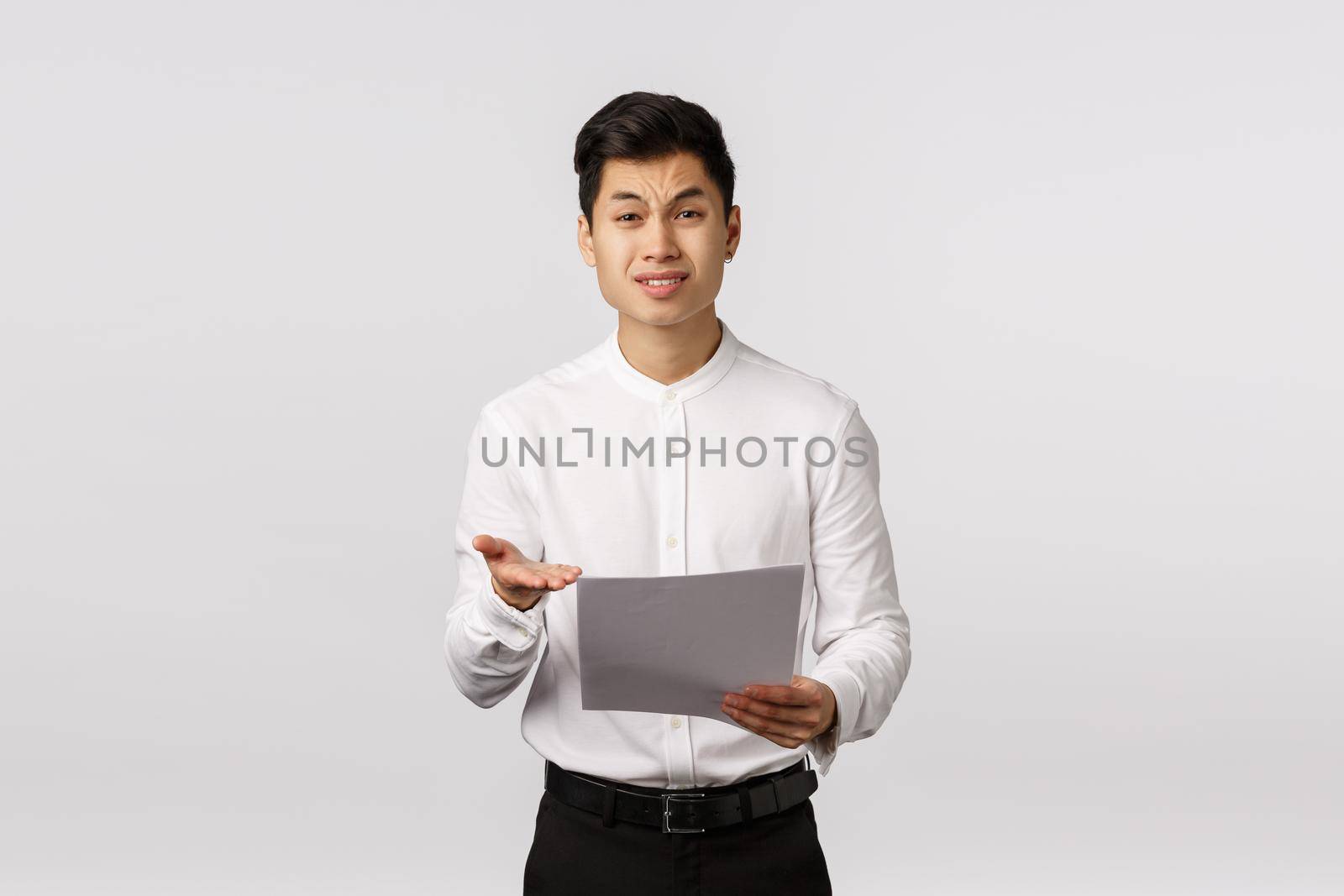 What is this. Displeased skeptical and unimpressed bossy asian businessman complaining employee made bad report, holding papers, pointing at documents and frimacing dislike, disapproval by Benzoix