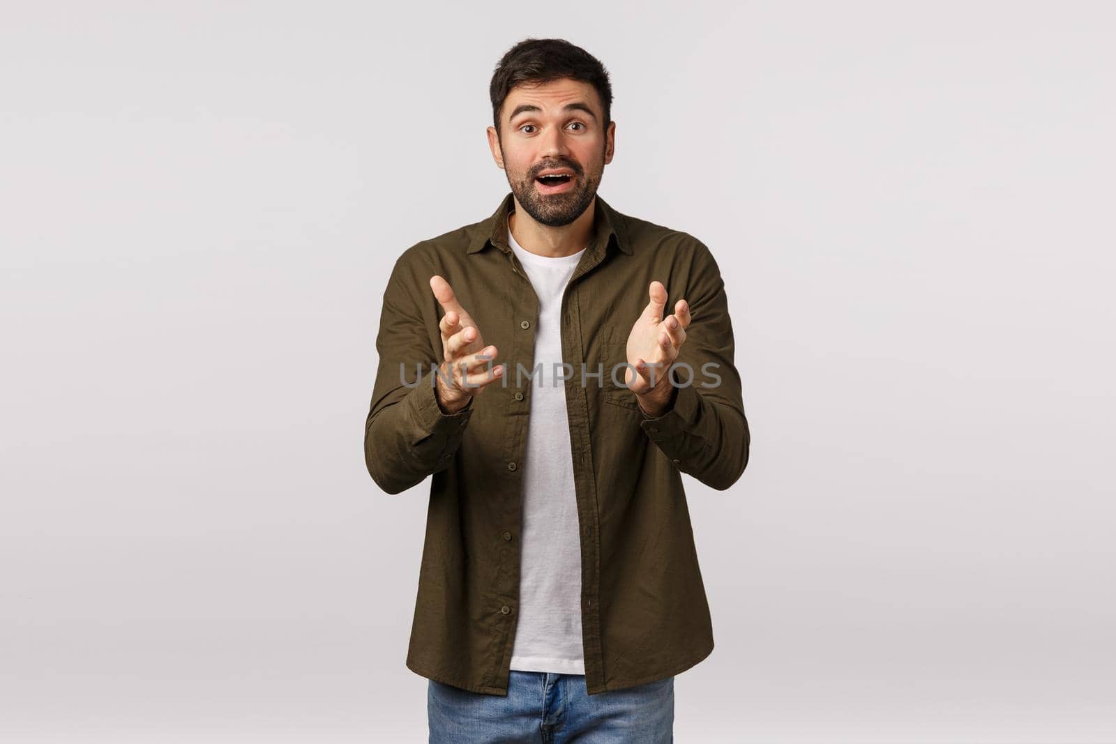Cheerful and relieved happy surprised young kind bearded man, describe his impressions and amazement, gesturing with hands as having conversation, smiling joyful, standing white background by Benzoix
