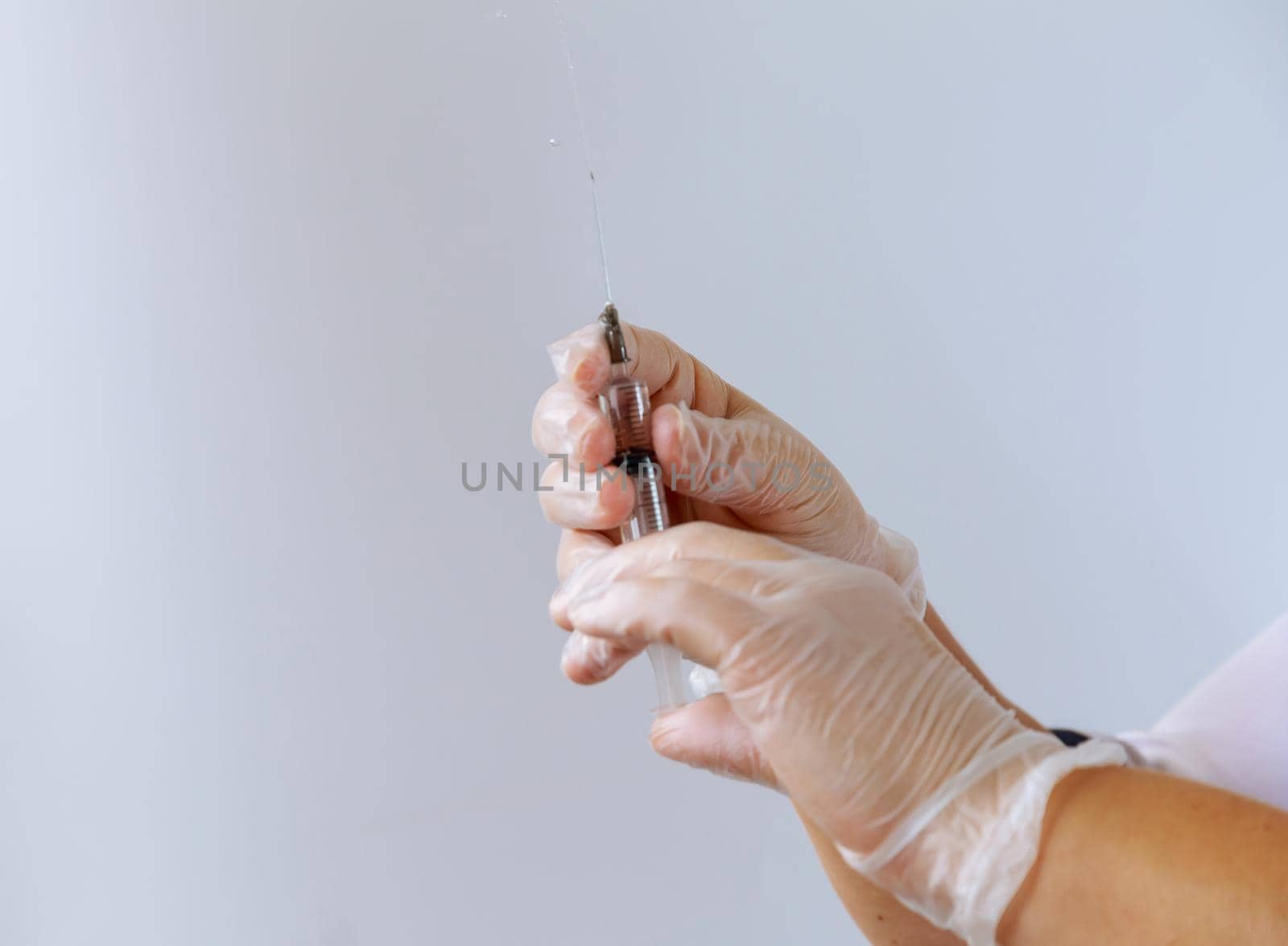 Nurse holds a syringe with liquid and releases air from a syringe on a white background. Intramuscular and venous injections.