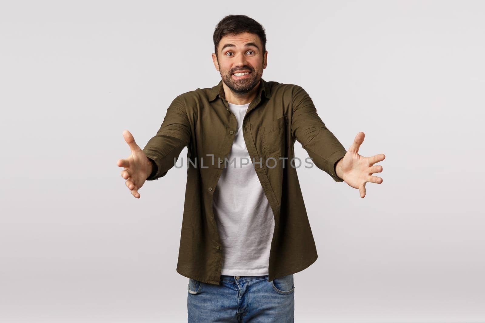 Lovely cheerful dad with beard in coat meeting his child in airport, spread hands sideways to cuddle someone, catch friend into his arms, smiling delighted, embracing loved one, white background.