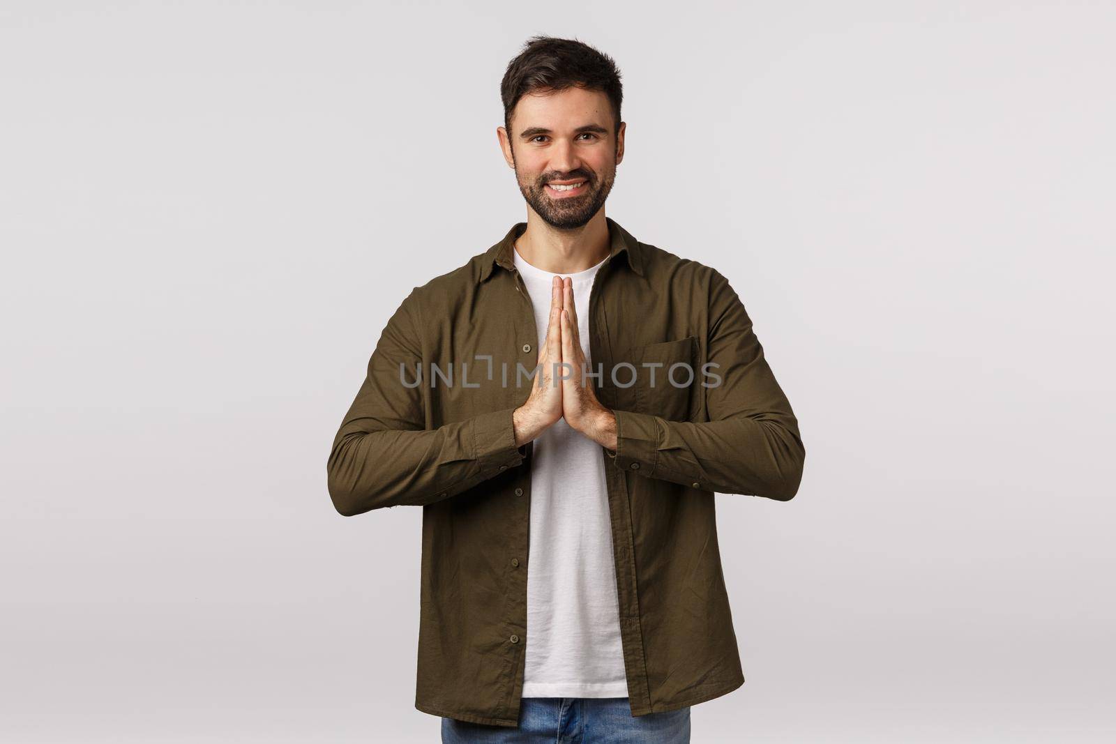 Cheerful, relaxed and friendly smiling caucasian man press palms together in pray, grinning, meditating or finish yoga practice, bowing to express gratitude sensei, standing white background.