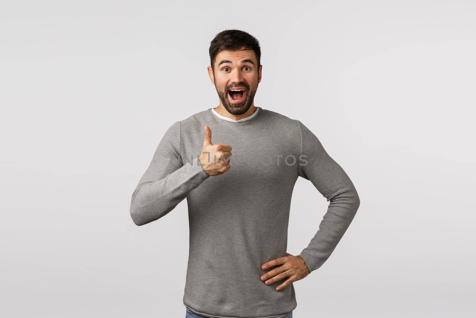Wonderful idea, lets do it. Excited, cheerful, supportive bearded adult man in grey sweater, give positive feedback, adore something really good, show thumb-up approval, like or enthusiastic gesture.