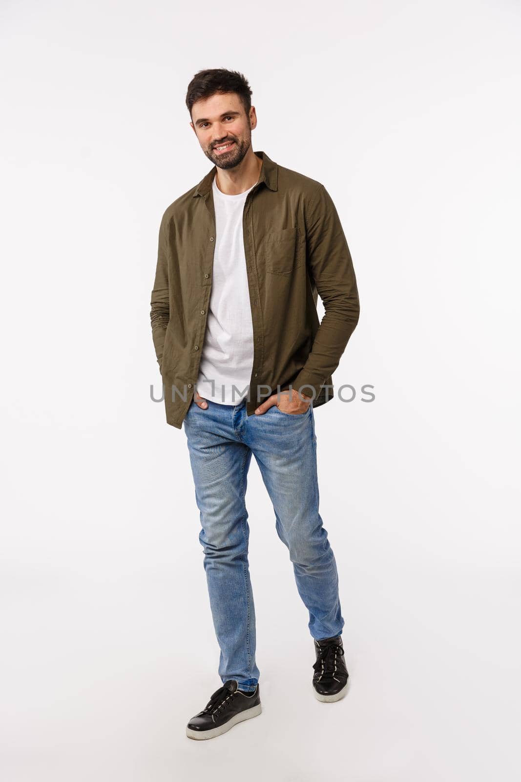 Full-length vertical shot good-looking macho stylish modern guy, unshaven, wear jeans and coat, strolling, walking city with hands in pockets, smiling cheeky, posing pleased over white background by Benzoix