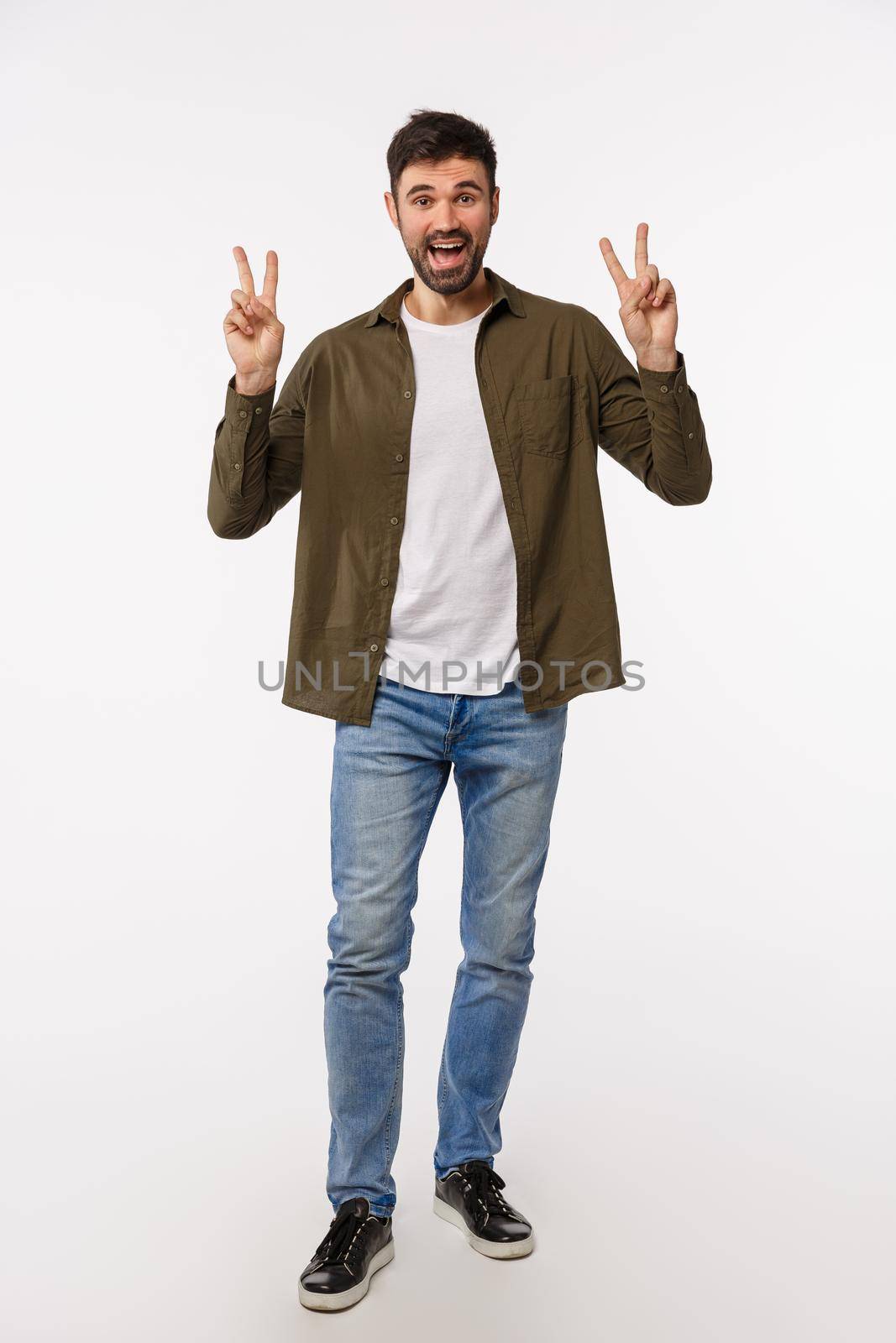 Vertical-shot full-length funny and attractive male model in jeans and coat making quotation gesture and smiling, show peace signs and express positive enthusiastic attitude, white background.
