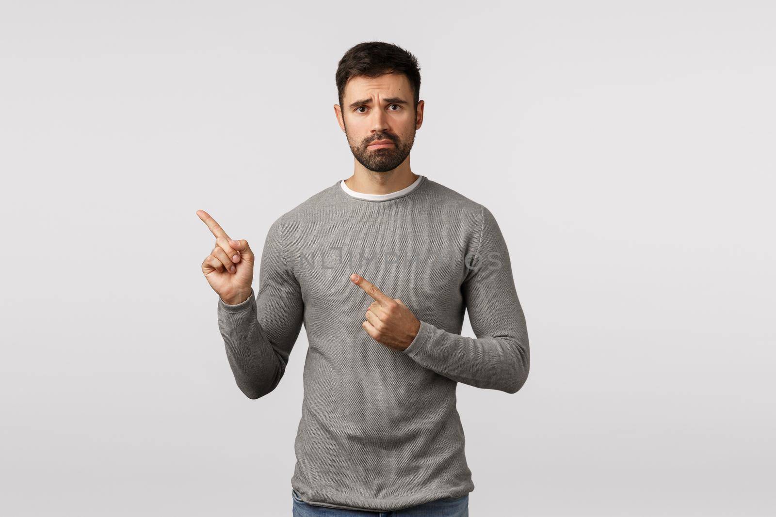 Depression, difficult situation and emotions concept. Sad, distressed and lonely bearded guy in grey sweater, frowning, look upset, pointing upper left corner with regret and disappointment by Benzoix