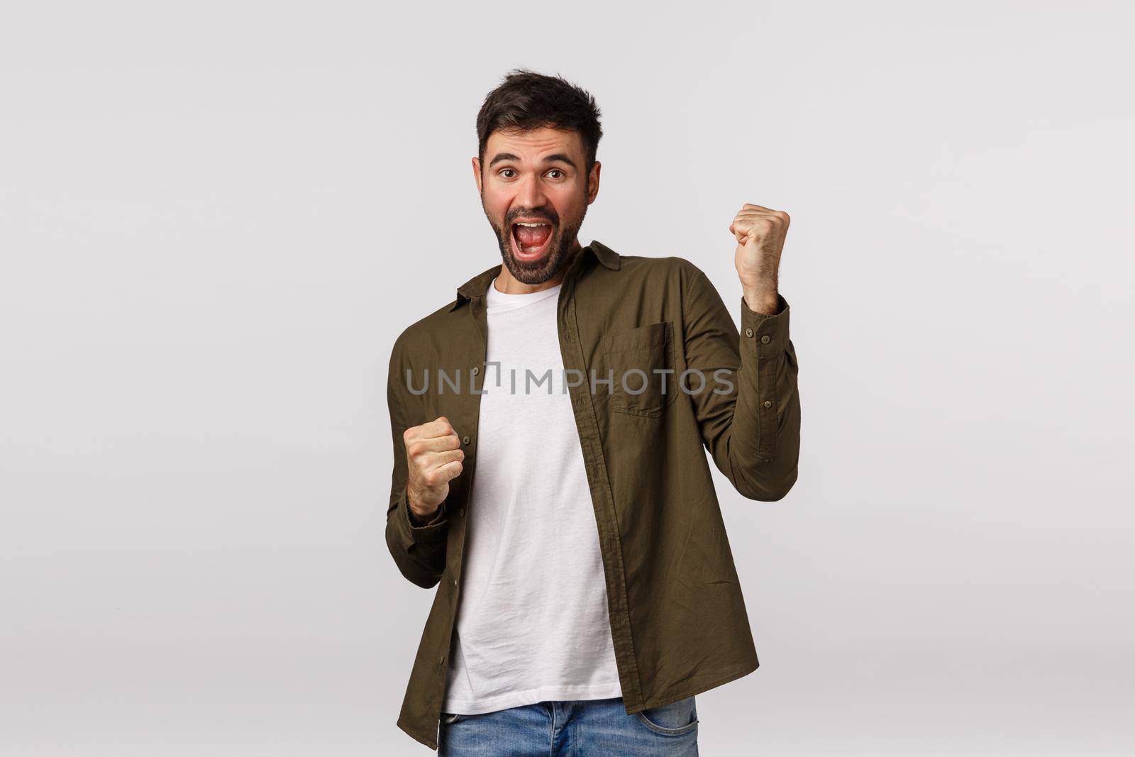 Relish, celebration and victory concept. Cheerful triumphing lucky businessman, guy winning, achieve prize or goal, have great news, fist pump and smiling, become champion, white background by Benzoix