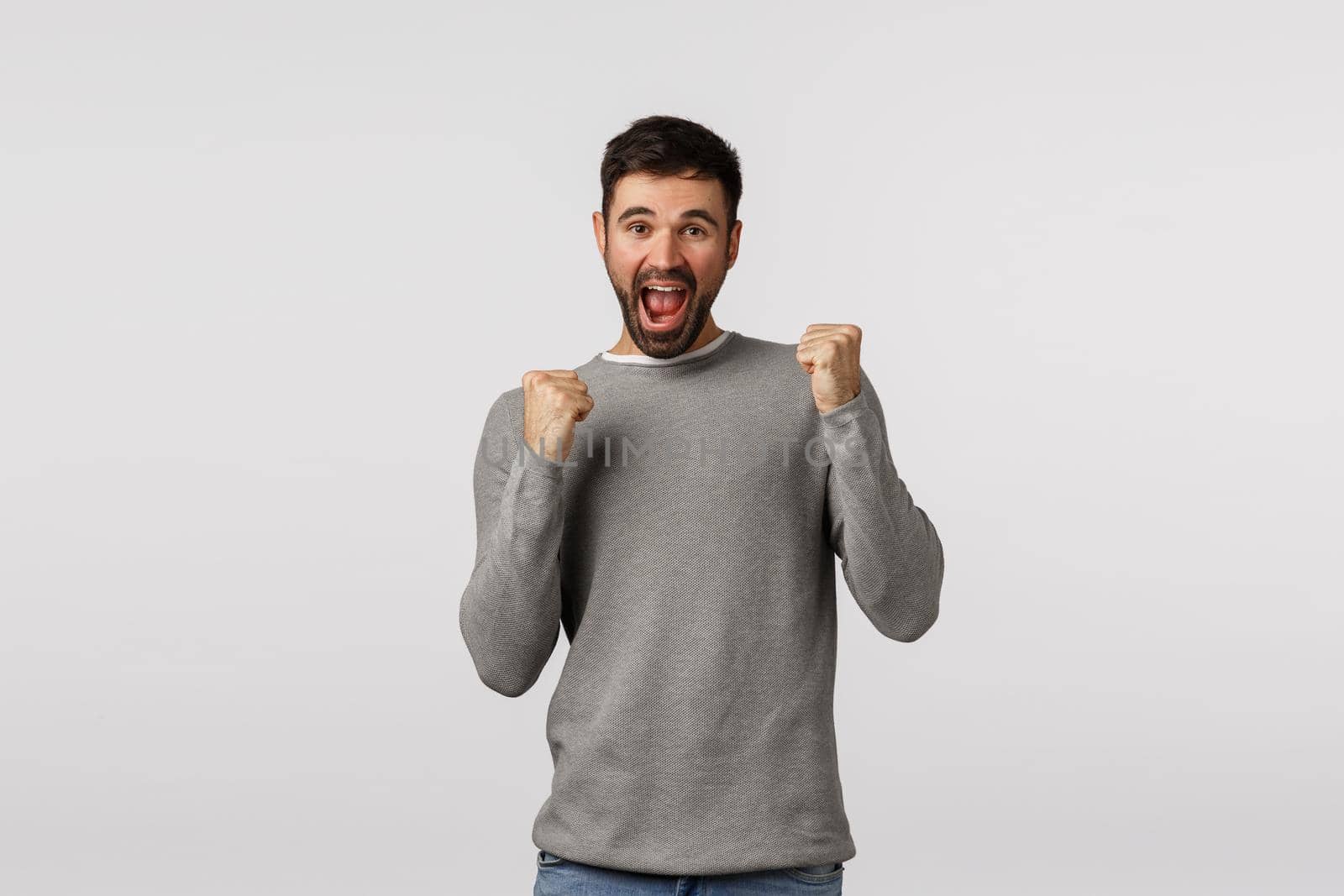 Celebration, luck and win concept. Cheerful optimistic caucasian guy in grey sweater celebrating good news, fist pump and joyfully smiling, congratulate friend, achieve goal, receive prize.
