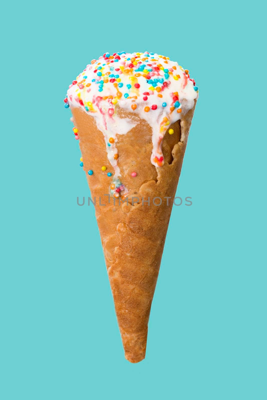 Ice cream cone close up. White ice cream scoop in a waffle cone on a blue background. Sweet dessert decorated with multicolored sprinkles