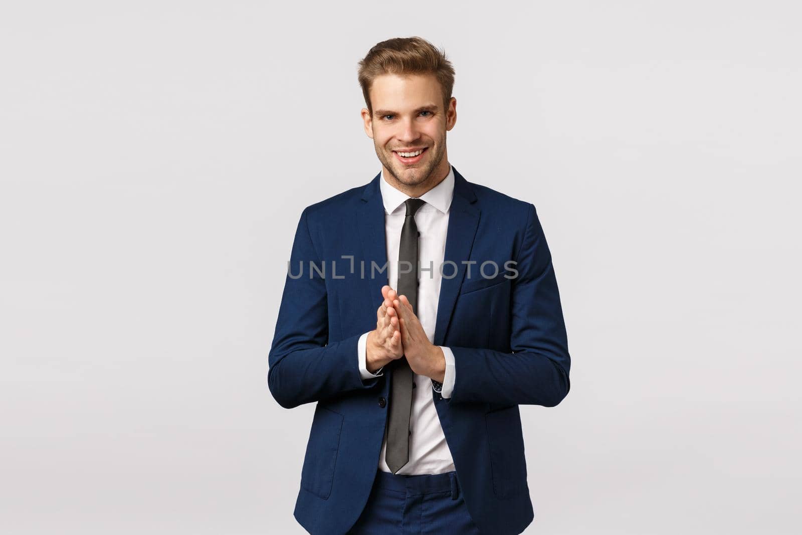 Time to make money. Corporate, finance and business concept. Good-looking blond bearded businessman, smiling pleased and lucky, relish good deal, rub hands, expect big news, white background.