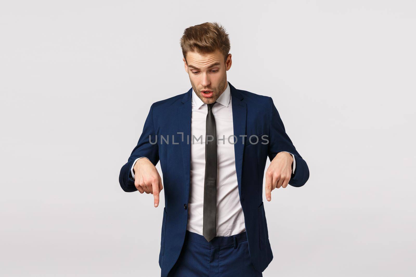 Shocked, impressed and curious blond bearded guy in classic suit, businessman pointing looking down speechless, standing astonished and impressed white background, check out product banner by Benzoix